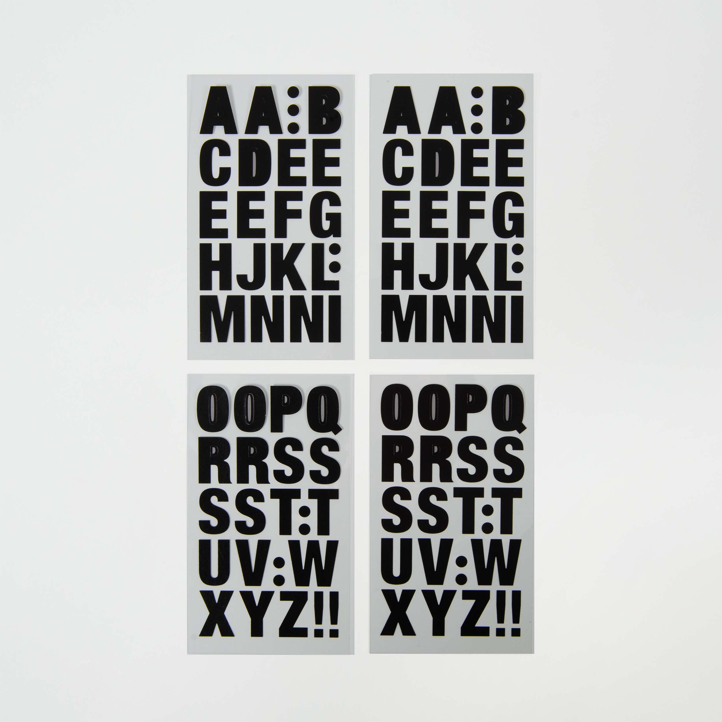 Vier weiße selbstklebende Buchstaben von Paper Poetry zeigen fette schwarze Großbuchstaben, die alphabetisch in zwei Reihen mit jeweils zwei Karten angeordnet sind, wobei sich wiederholende Buchstaben Spalten darüber bilden.