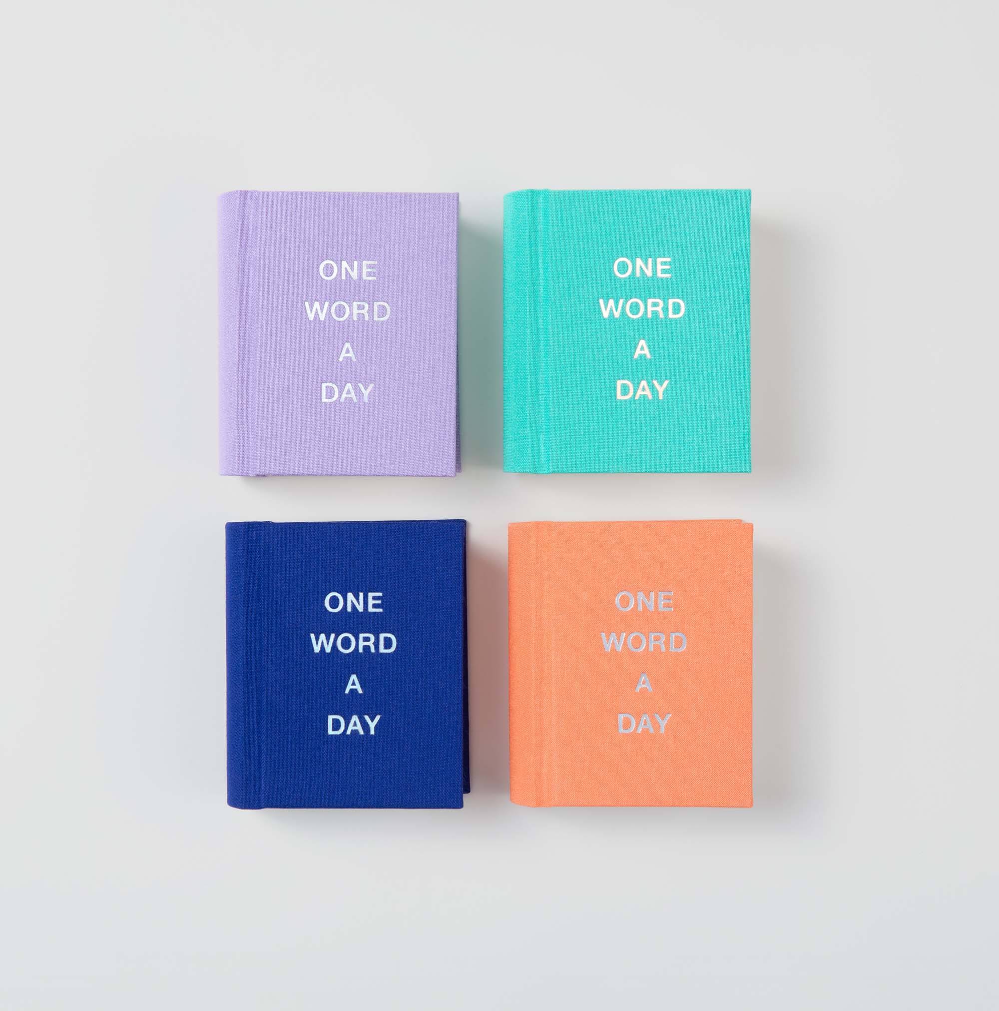 Vier kleine OWAD Shine Bright Mini-Notizbücher mit festem Einband von paperlux sind in einem Quadrat auf weißem Hintergrund angeordnet. Auf jedem Einband steht "One Word a Day" und die lavendelfarbenen, blaugrünen, marineblauen und orangefarbenen Bücher sind ein ideales Geschenk für jeden Anlass.