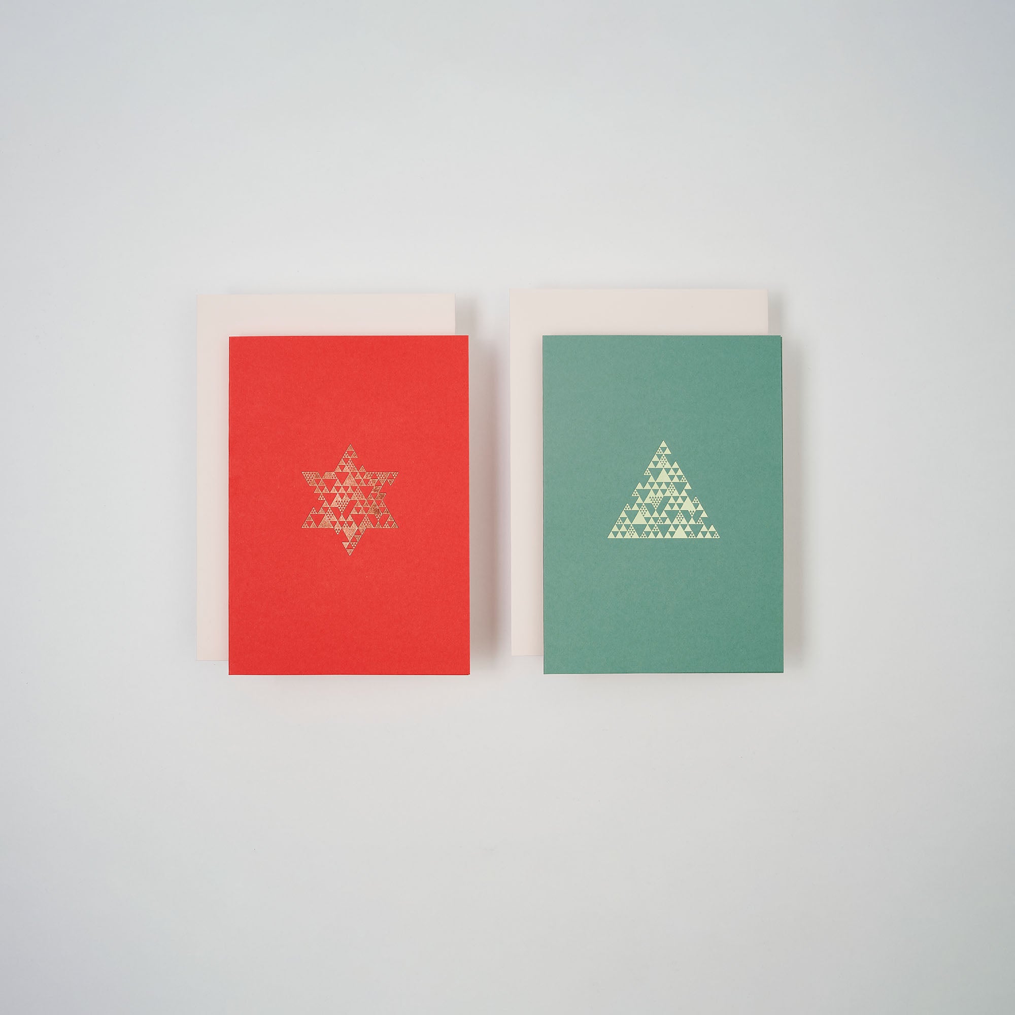 Das Weihnachtskarten 2er-Set Coral & Sage von paperlux.store enthält eine korallfarbene A6-Karte mit goldenem Davidstern und eine salbeifarbene Karte mit goldenem Dreiecksmuster, jeweils mit passenden weißen Umschlägen.