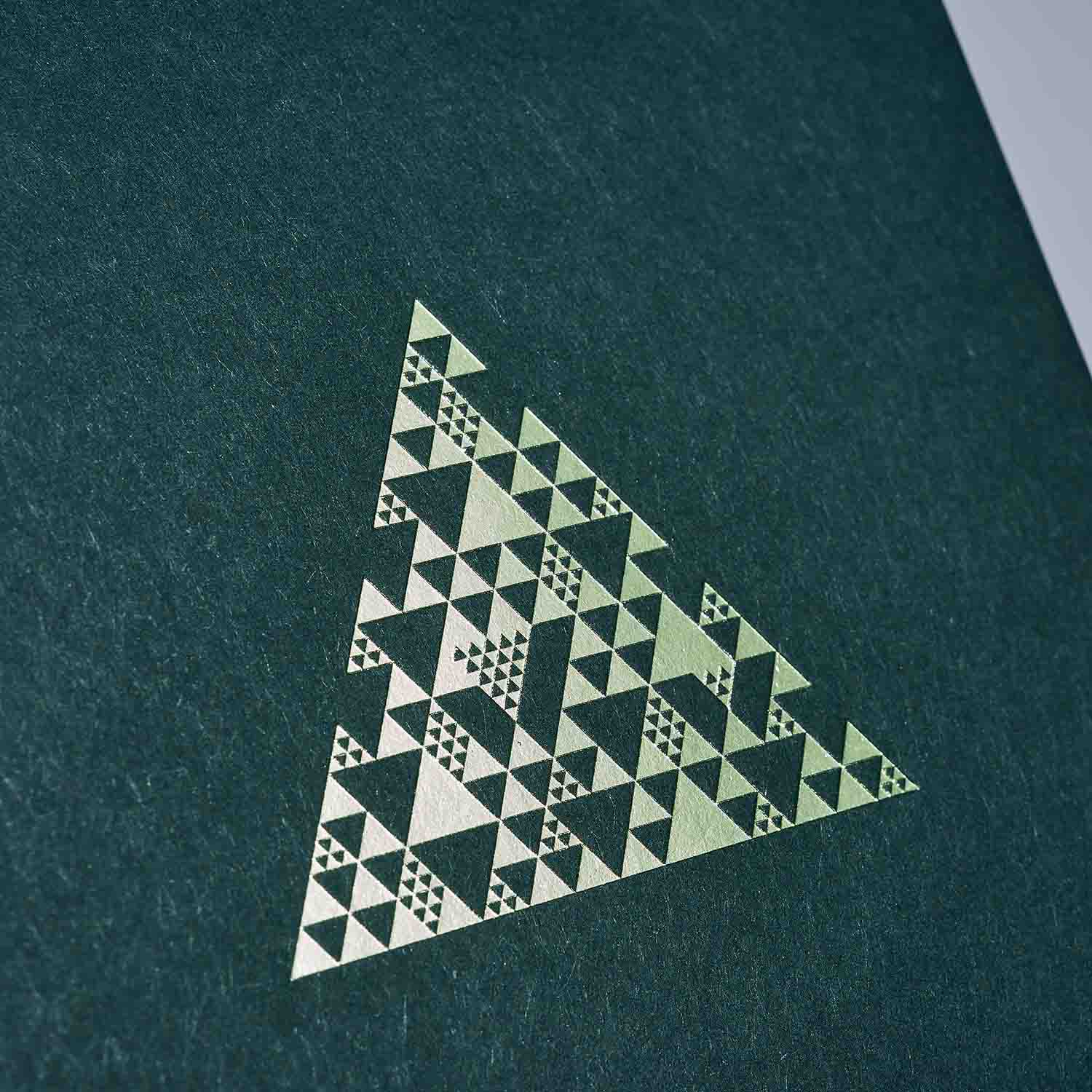 Ein metallisch-goldenes Dreieck mit geometrischen Mustern ziert einen strukturierten dunkelgrünen Hintergrund. Damit ist das paperlux.store Weihnachtskarten 2er-Set Snow & Green perfekt für festliche Grüße.