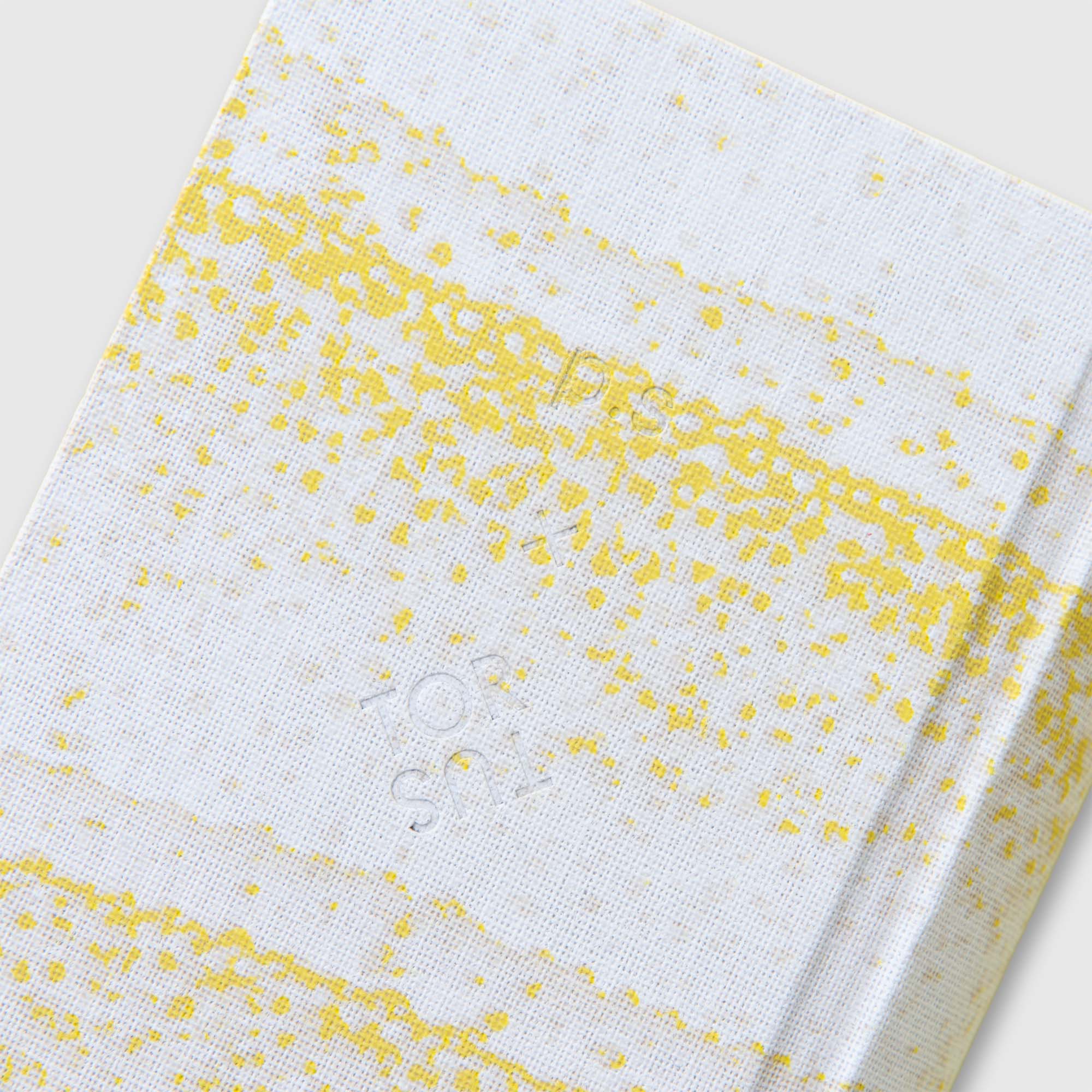 Ein weißes, strukturiertes Cover mit gelben Sprenkeln und subtilen Linien - OWAD x TORTUS Limited Edition by paperlux.store - mit geprägtem, kaum sichtbarem Text in der Mitte, der die handwerkliche Essenz von TORTUS Copenhagen widerspiegelt.