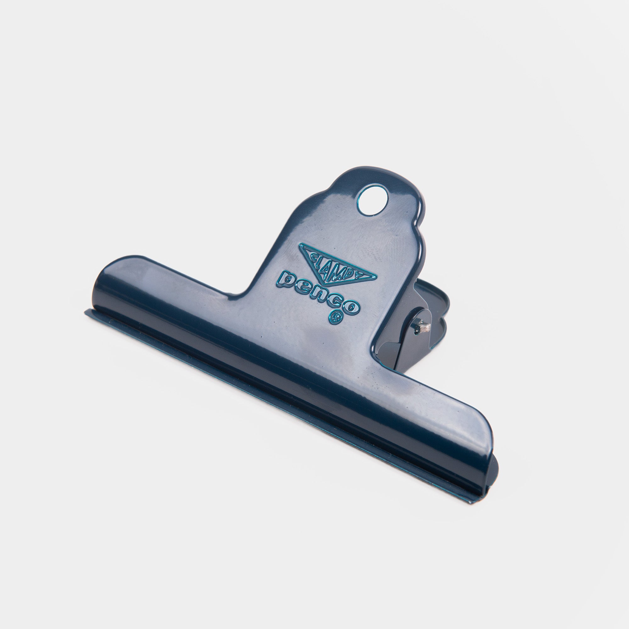 Ein großer, dunkelblauer Metallclip - Clampy Clip M von Penco - ist mit einem Rautenlogo versehen und steht auf einem schlichten weißen Hintergrund; perfekt für Fans von Penco- oder Metallclip-Designs.