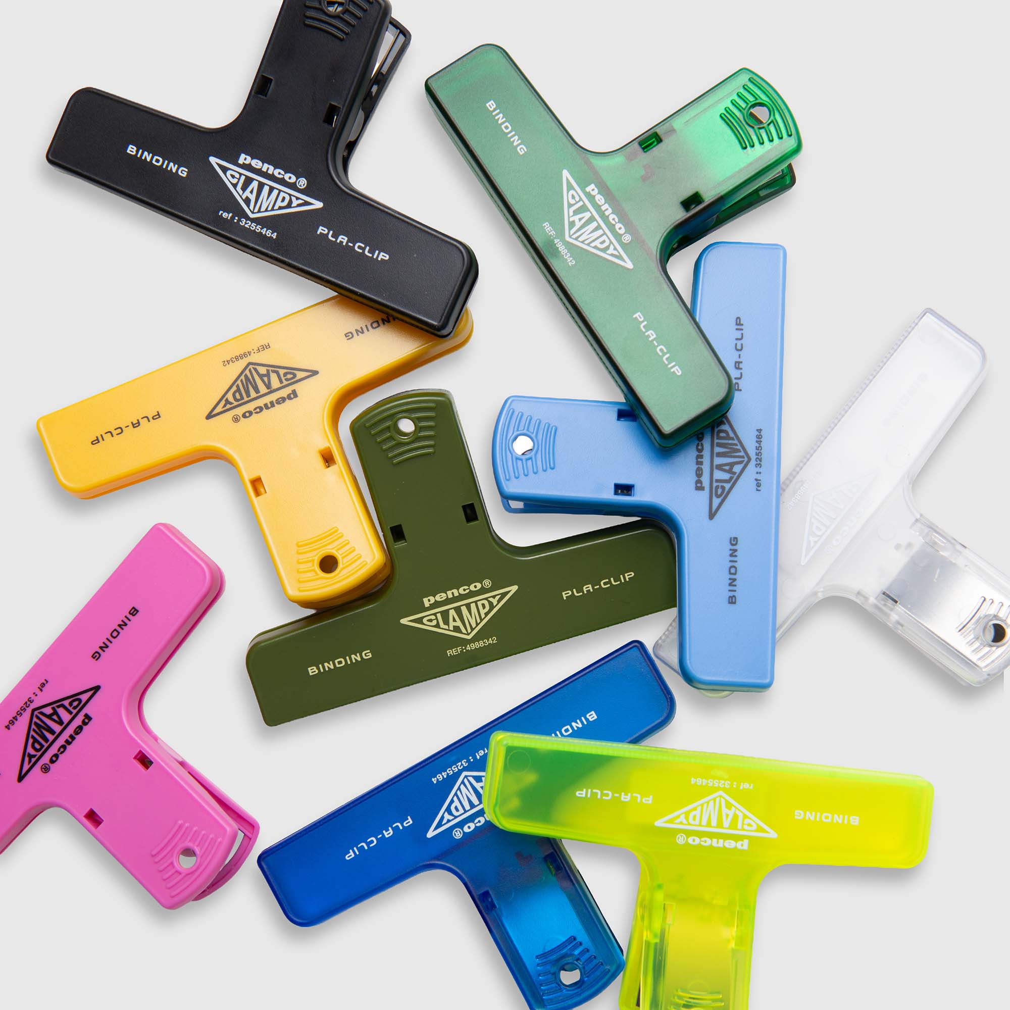 Neun farbenfrohe Penco Clampy PlaClip-Bindeklammern Kunststoff sind auf einer weißen Fläche verteilt. Diese aus strapazierfähigem ABS-Kunststoff gefertigten Klammern sind in den Farben Rosa, Gelb, Blau, Grün, Schwarz und Transparent erhältlich. Jeder Clip zeichnet sich durch ein markantes dreieckiges Design aus und ist mit den Aufschriften „Penco Clamp“ und „Binding PLA-Clip“ versehen, was die zuverlässige Qualität der Clampy-Clip-Kollektion von Penco unterstreicht.
