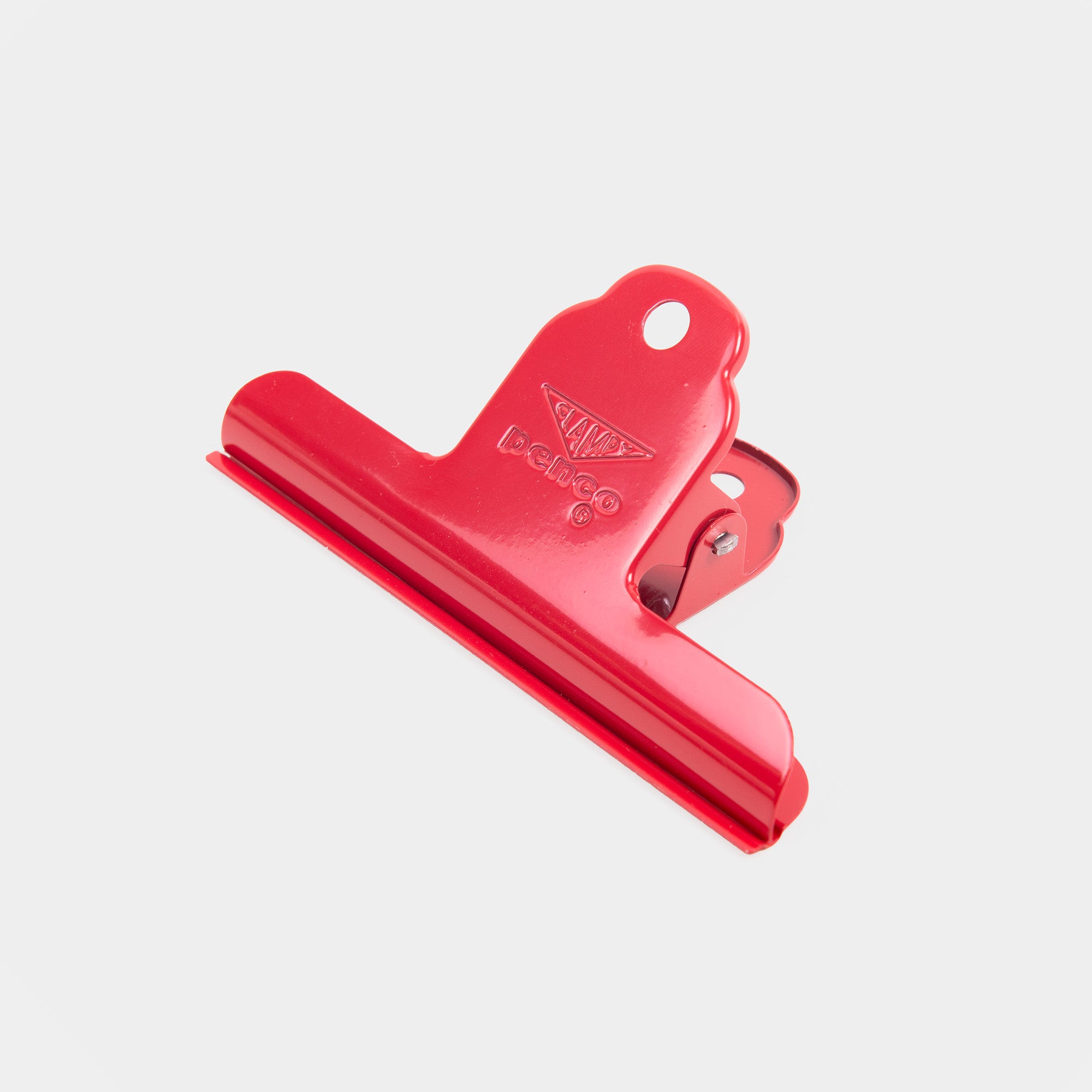 Ein großer roter Clampy Clip M Binder Clip von Penco mit einem dreieckigen Griff und einem Aufhängeloch wird vor einem schlichten weißen Hintergrund gezeigt.
