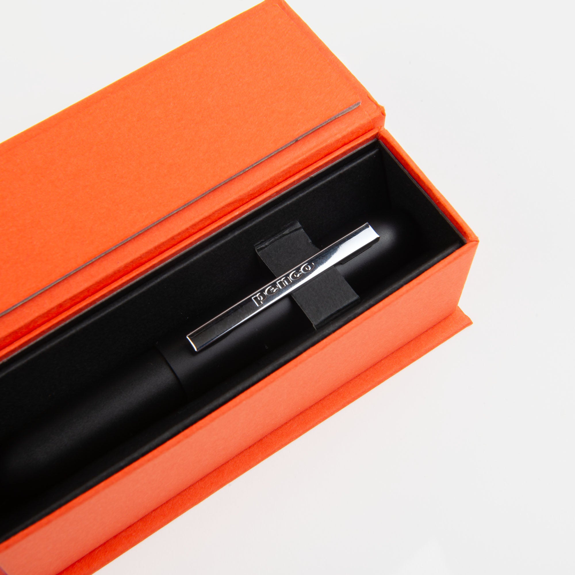 Der Kompakt-Kugelschreiber - Bullet Pen schwarz von paperlux.store mit silbernem Clip liegt in einer schwarz-orangen Geschenkbox. Das Messinggehäuse sorgt für Eleganz und Langlebigkeit.