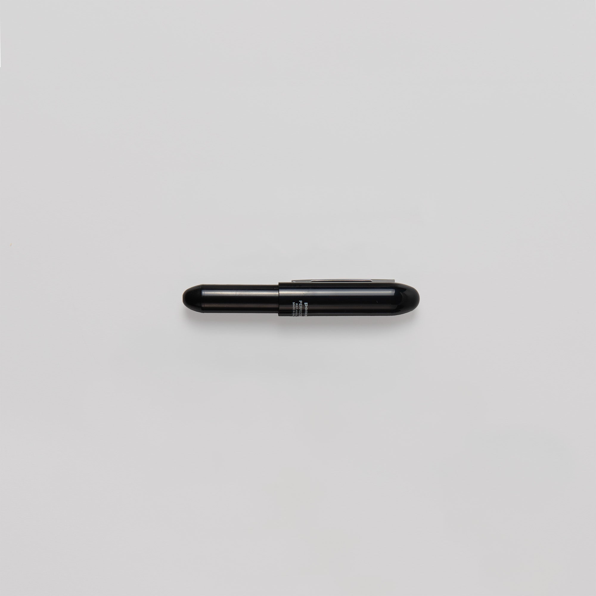 Ein kleiner, schwarzer Bullet-Kugelschreiber von Penco, kapselförmig mit glänzender Oberfläche, steht zentriert vor einem schlichten weißen Hintergrund. Auf ihm steht „Made in Japan“.