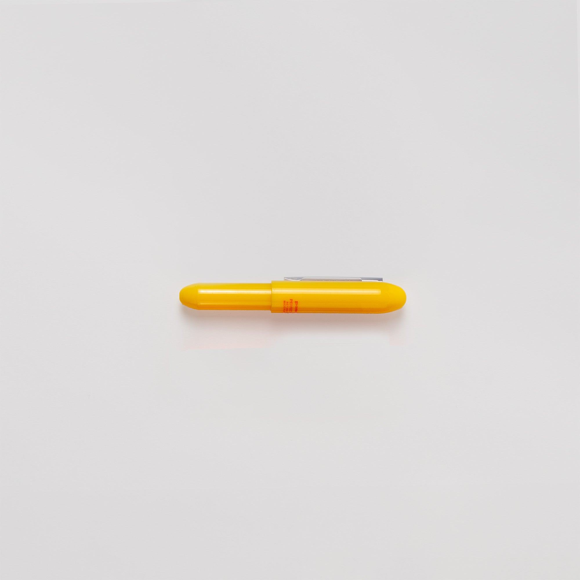 Ein kompakter gelber Bullet-Kugelschreiber von Penco mit feiner Spitze und silbernem Clip mit der Aufschrift „Kleiner Stift“ liegt horizontal auf einer schlichten weißen Oberfläche. Hergestellt in Japan, verbindet er Funktionalität mit Eleganz.