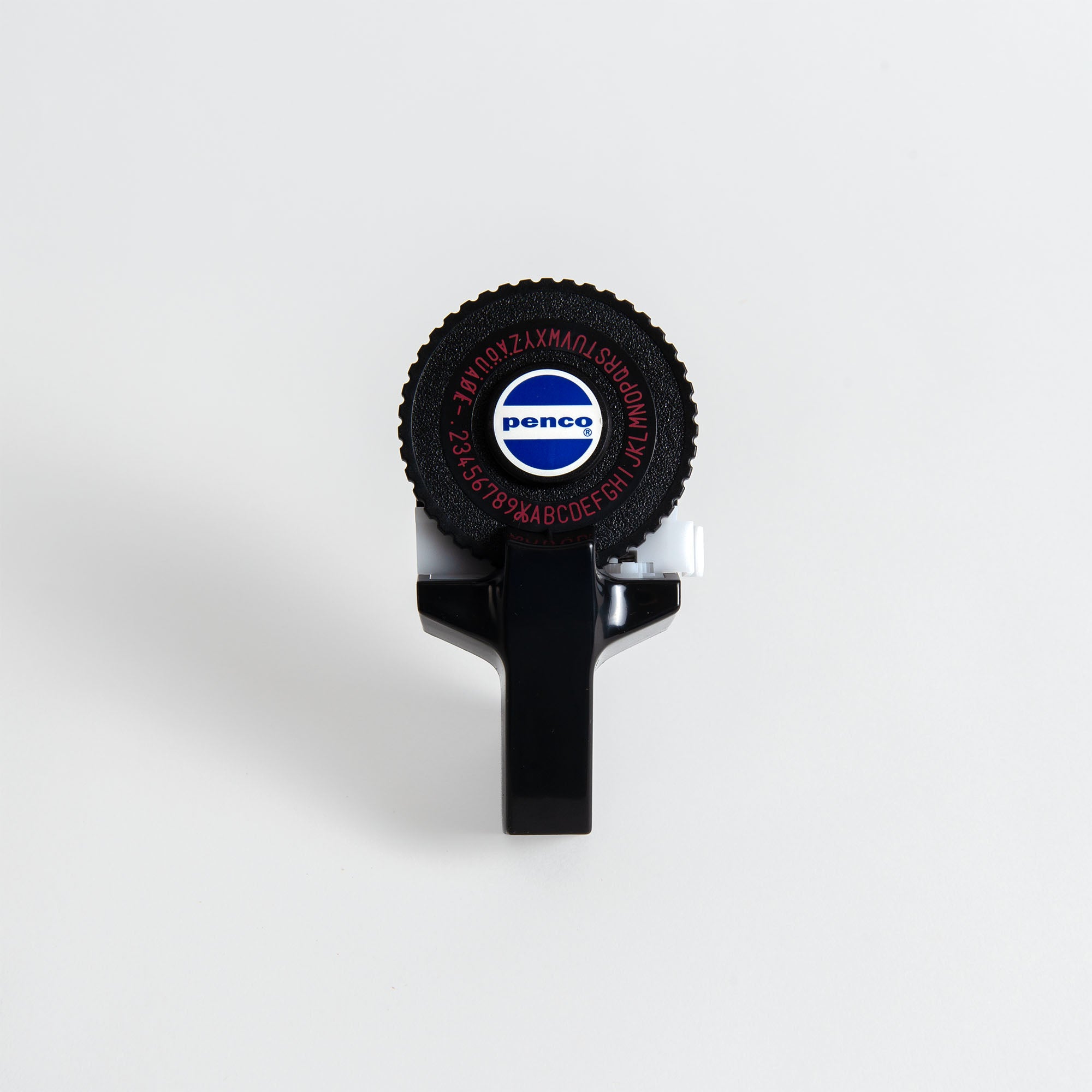 Ein schwarzes, handgeführtes Penco Tape Writer-Etikettengerät von Penco mit einem runden Ziffernblatt mit Buchstaben und Zahlen und einem zentralen weißen Aufkleber mit dem blauen Penco-Logo ist vor einem weißen Hintergrund abgebildet.