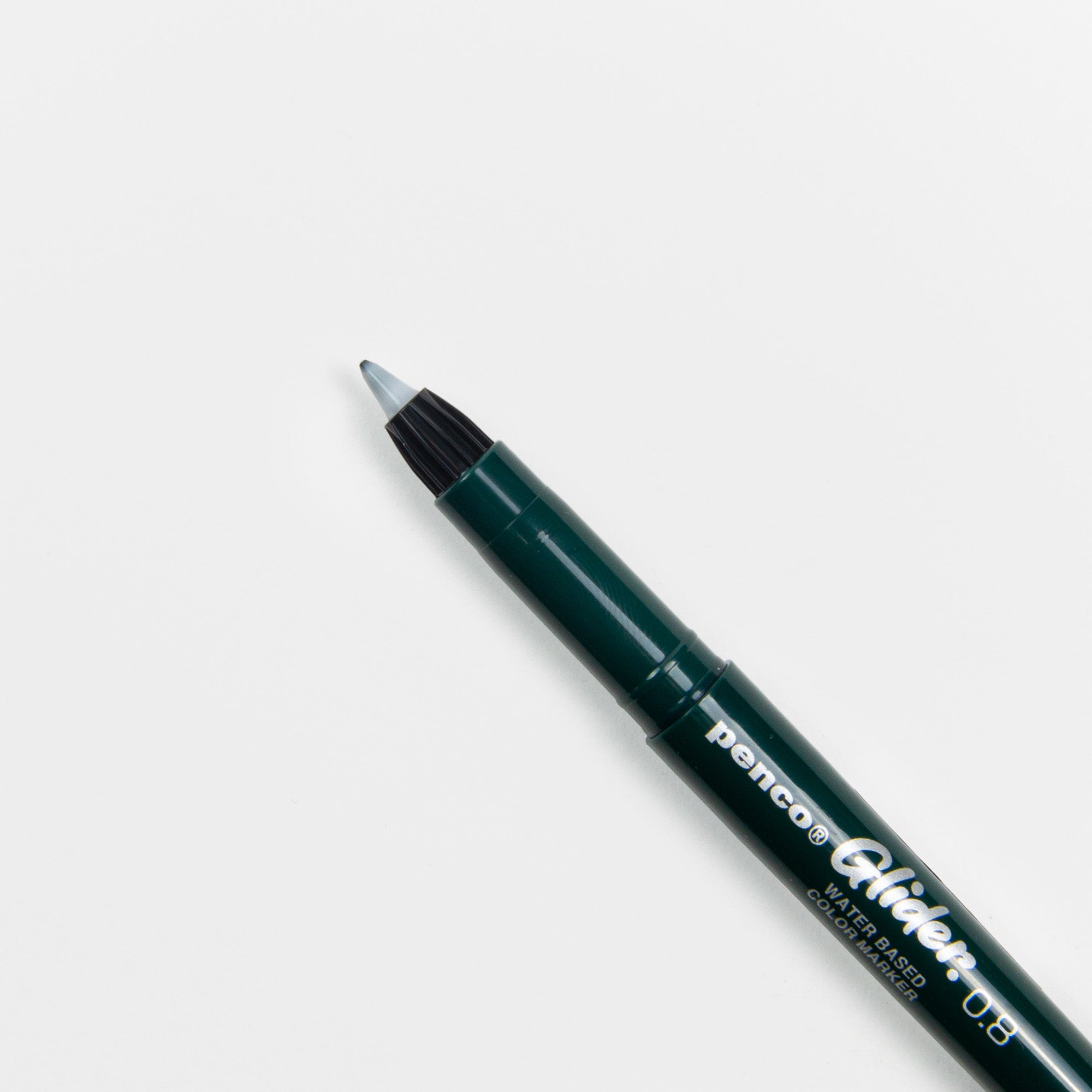 Ein dunkelgrüner Penco Glider Colour Pen mit Tinte auf Wasserbasis liegt schräg auf einer weißen Fläche, die Kappe ist abgenommen und gibt den Blick auf die feine Spitze frei.