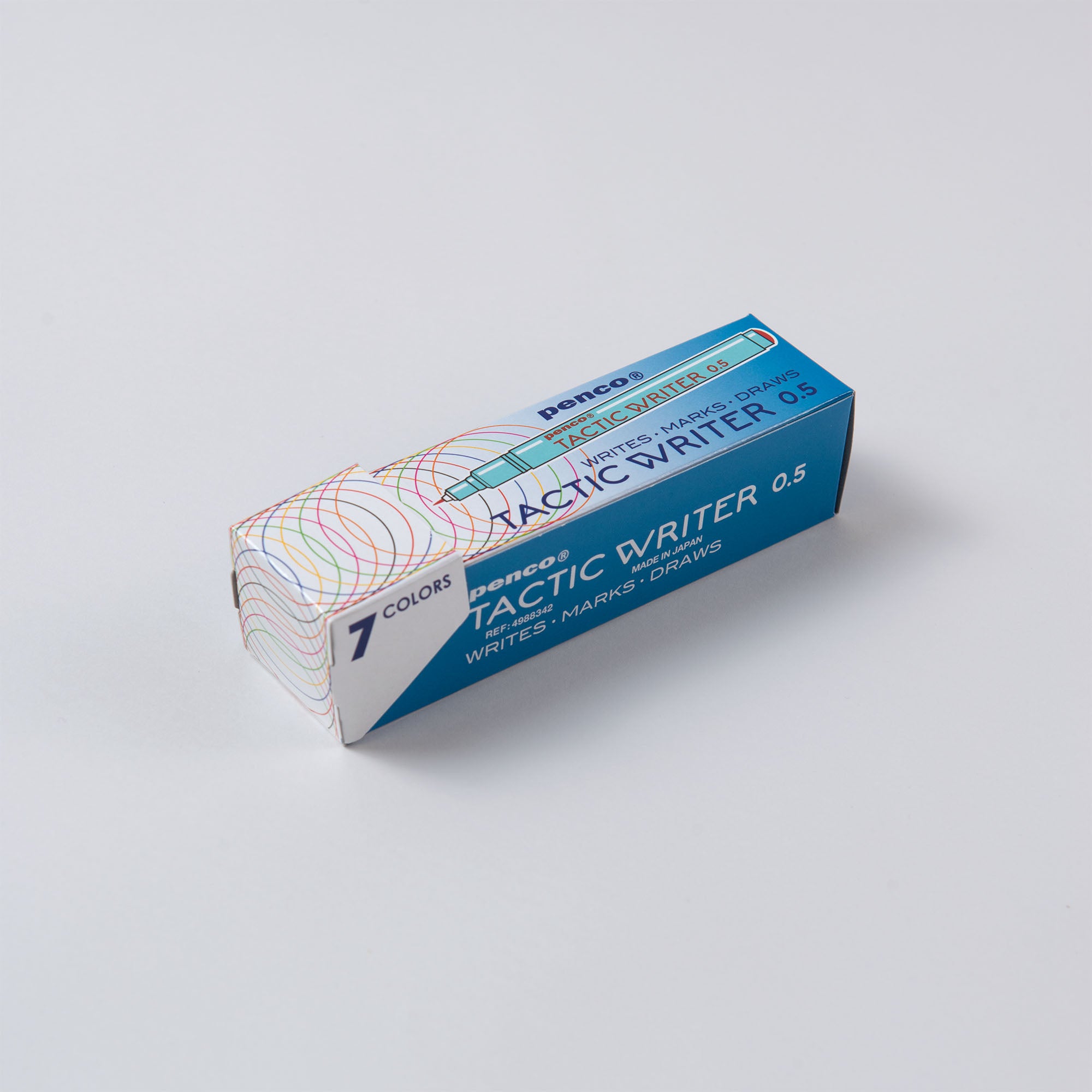 Auf einer glatten Oberfläche liegt ein Penco Tactic Writer Set mit sieben Farben in überwiegend blauer Verpackung mit mehrfarbigen Kreismustern. Es enthält Tinte auf Wasserbasis, perfekt für Kalligrafie, und trägt den Text: „7 Farben zum Schreiben, Markieren, Zeichnen.