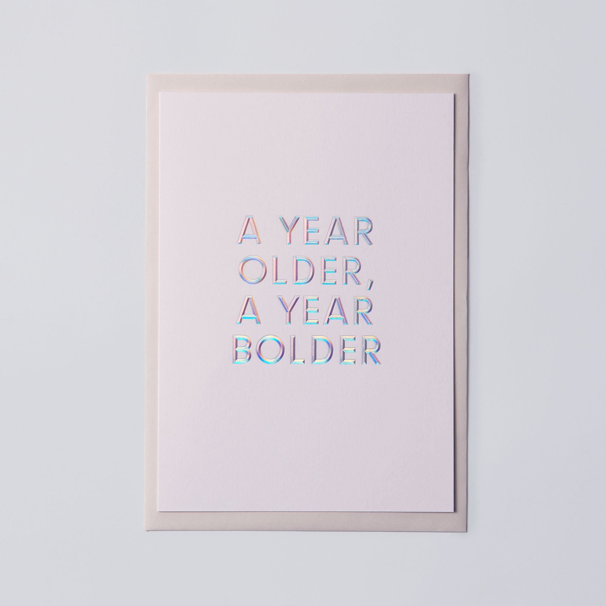 Die Geburtstagskarte „AYOAYB“ von paperlux.store zeigt „A YEAR OLDER, A YEAR BOLDER“ in irisierender Heißfolienprägung auf schlichtem Hintergrund.