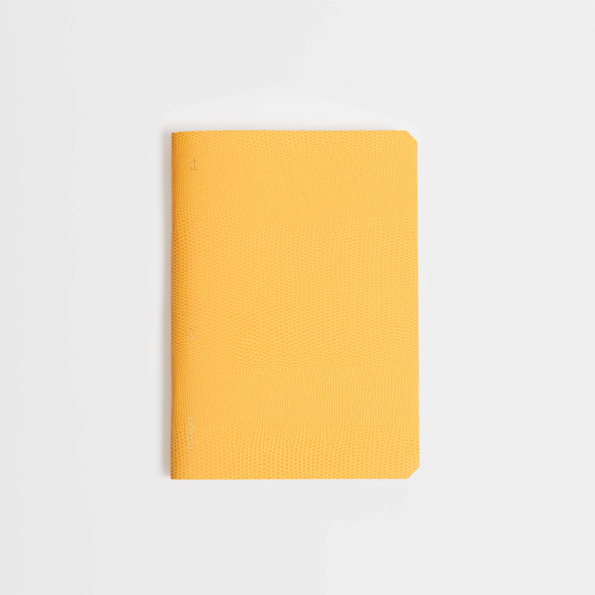 Das geschlossene Softcover-Notizbuch B96 Mellow Yellow von paperlux.store mit abgerundeten Ecken ruht auf einem schlichten weißen Hintergrund und strahlt dezente Eleganz aus.