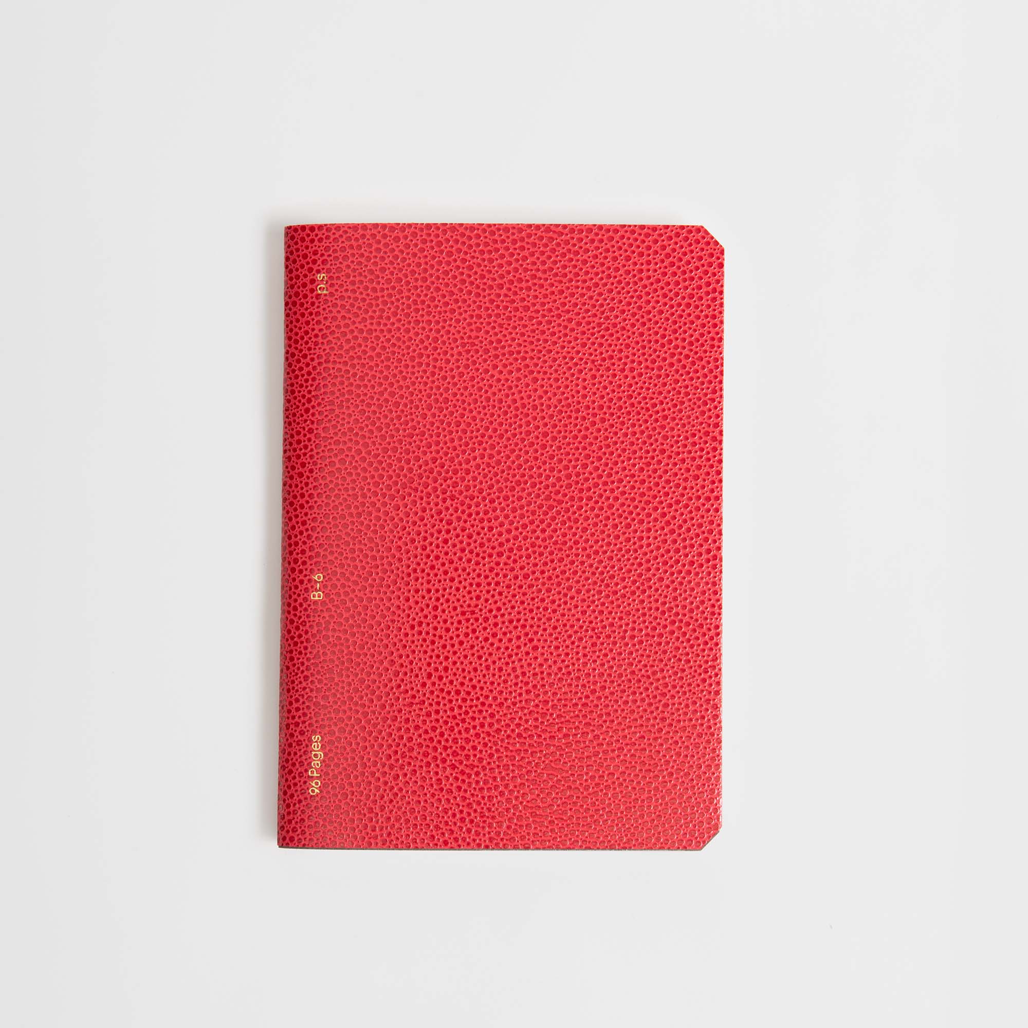 Ein geschlossenes B96 Red Lipstick Softcover Notizbuch von paperlux.store mit rotem, strukturiertem Einband und kleinem goldenen Rückentext, zentriert auf einem schlichten weißen Hintergrund.