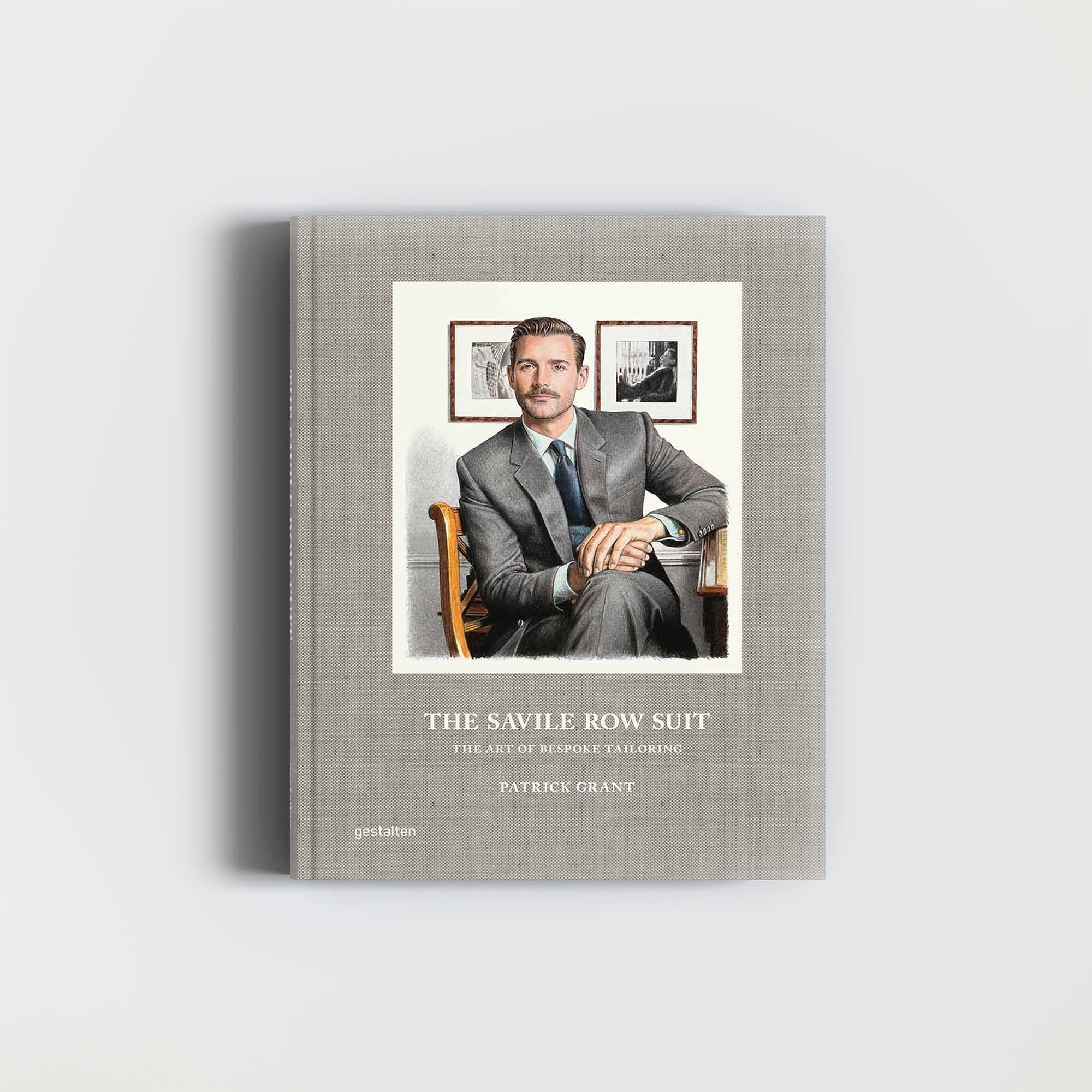 Das Buch „The Savile Row Suit“ vom Gestalten Verlag zeigt auf dem Cover einen Mann im Anzug in einem Stuhl vor einem grauen Hintergrund mit gerahmten Fotos, der die Essenz maßgeschneiderter Schneiderkunst einfängt.