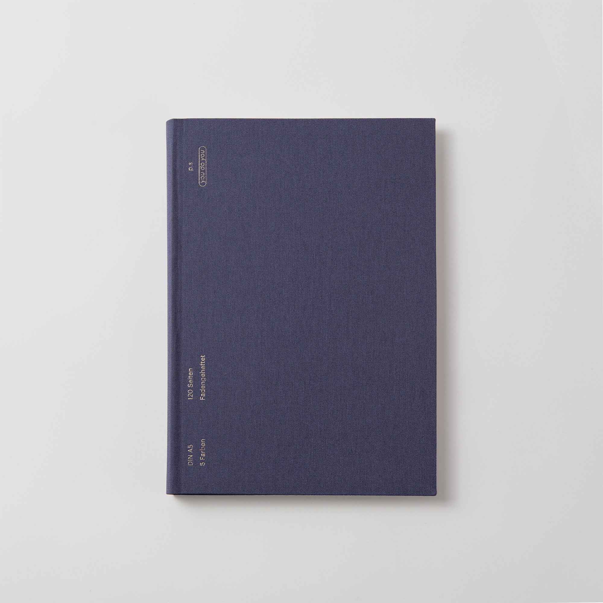 Das Notanizer Notizbuch A5 von paperlux.store ruht in geschlossener dunkelblauer Eleganz auf einer weißen Oberfläche. Mit minimalem goldenen „You do You“-Text und glatten Farbschnittkanten strahlt es eine professionelle Aura aus.