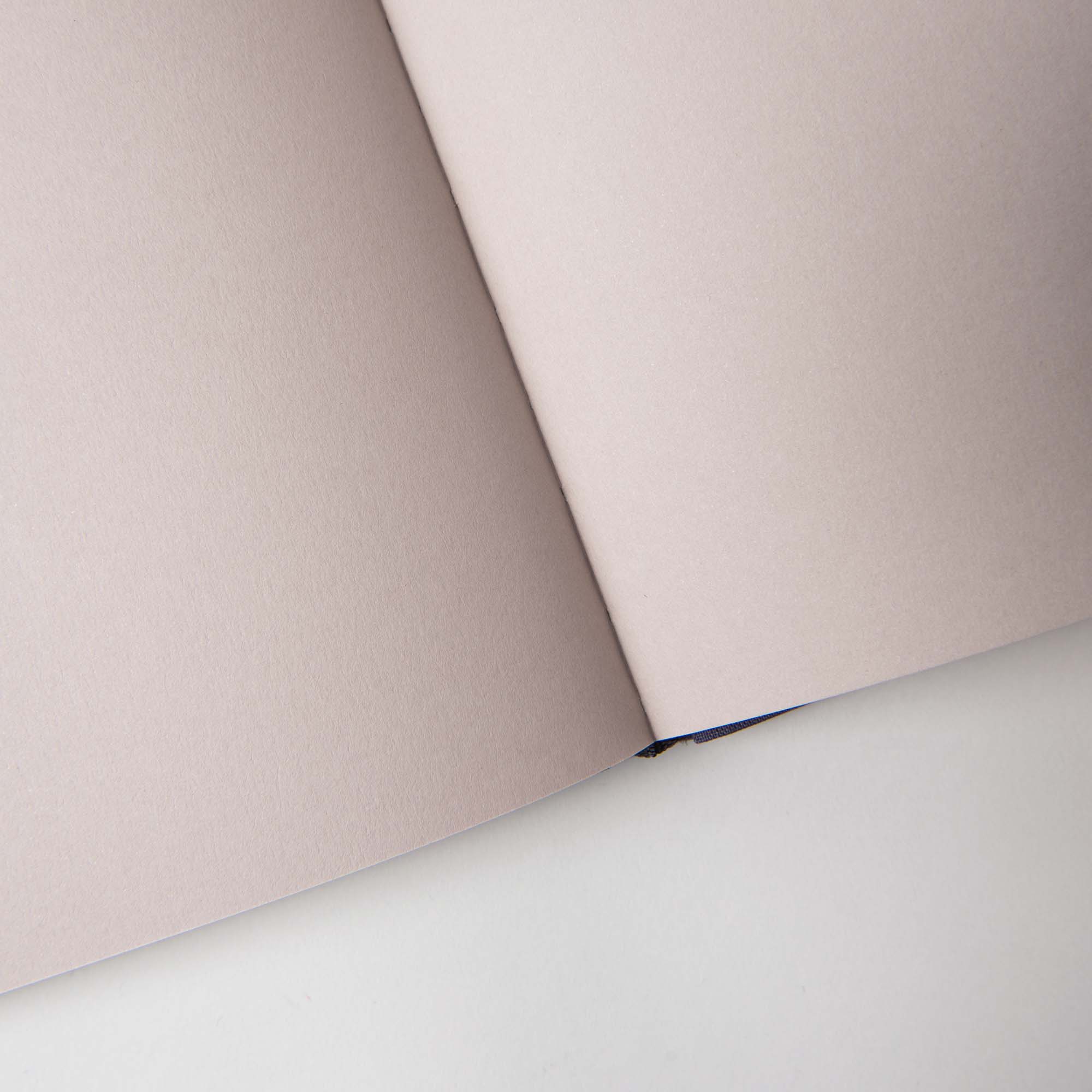 Das Notanizer Notizbuch A5 von paperlux.store in edler Feinstpapier-Qualität ruht mit seinen aufgeschlagenen beigen Seiten auf einem hellen Untergrund.
