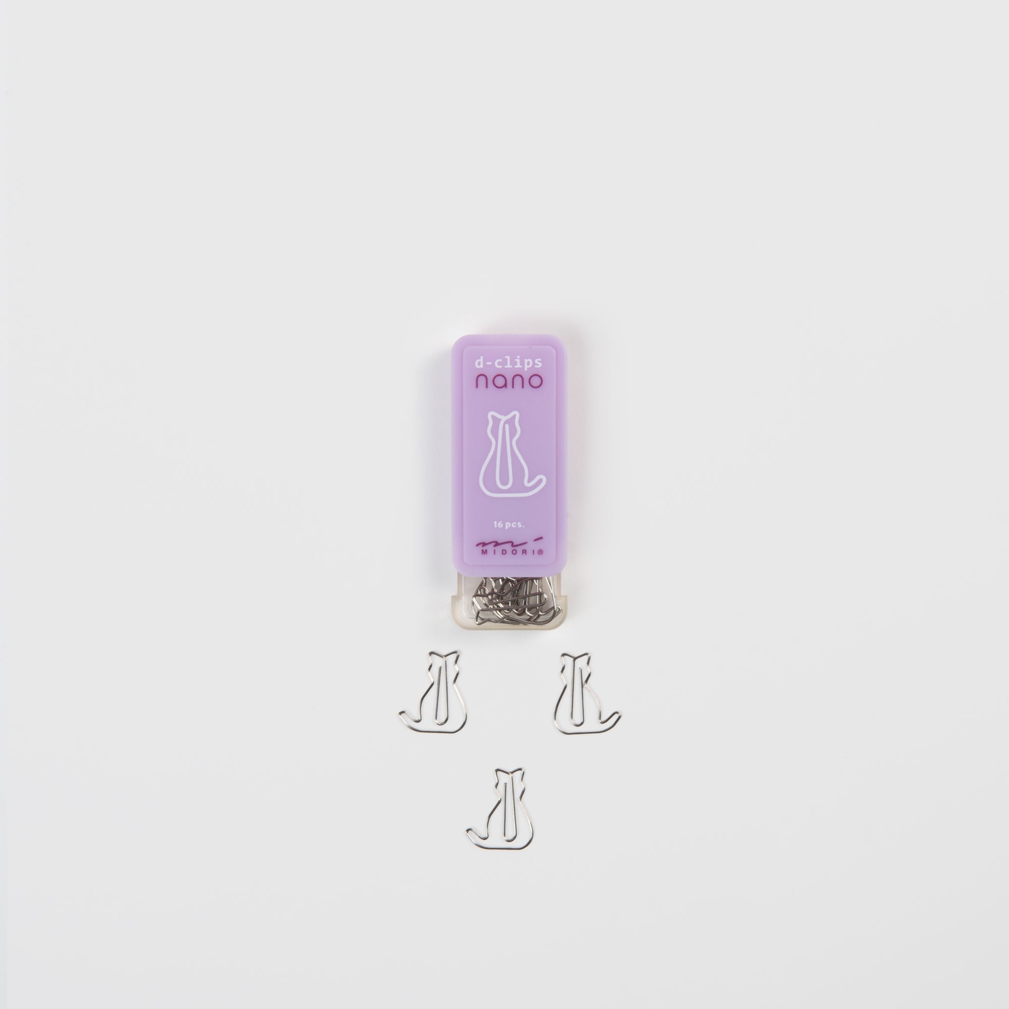 Die D-Clips Nano: Katze von Midori ist ein kleiner lilafarbener Behälter mit einem Katzenmotiv, der silberne, katzenförmige Clips enthält - ideales Schreibtisch-Zubehör für den Arbeitsbereich eines jeden Katzenliebhabers.