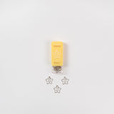 Eine geöffnete Schachtel mit sternförmigen Büroklammern liegt auf weißem Grund. Die gelbe Verpackung mit der Aufschrift „D-Clips Nano: Sterne“ von Midori eignet sich ideal, um Notiz- oder Liebesbriefen einen besonderen Charme zu verleihen. Unter der Schachtel sind drei Klammern übersichtlich angeordnet.