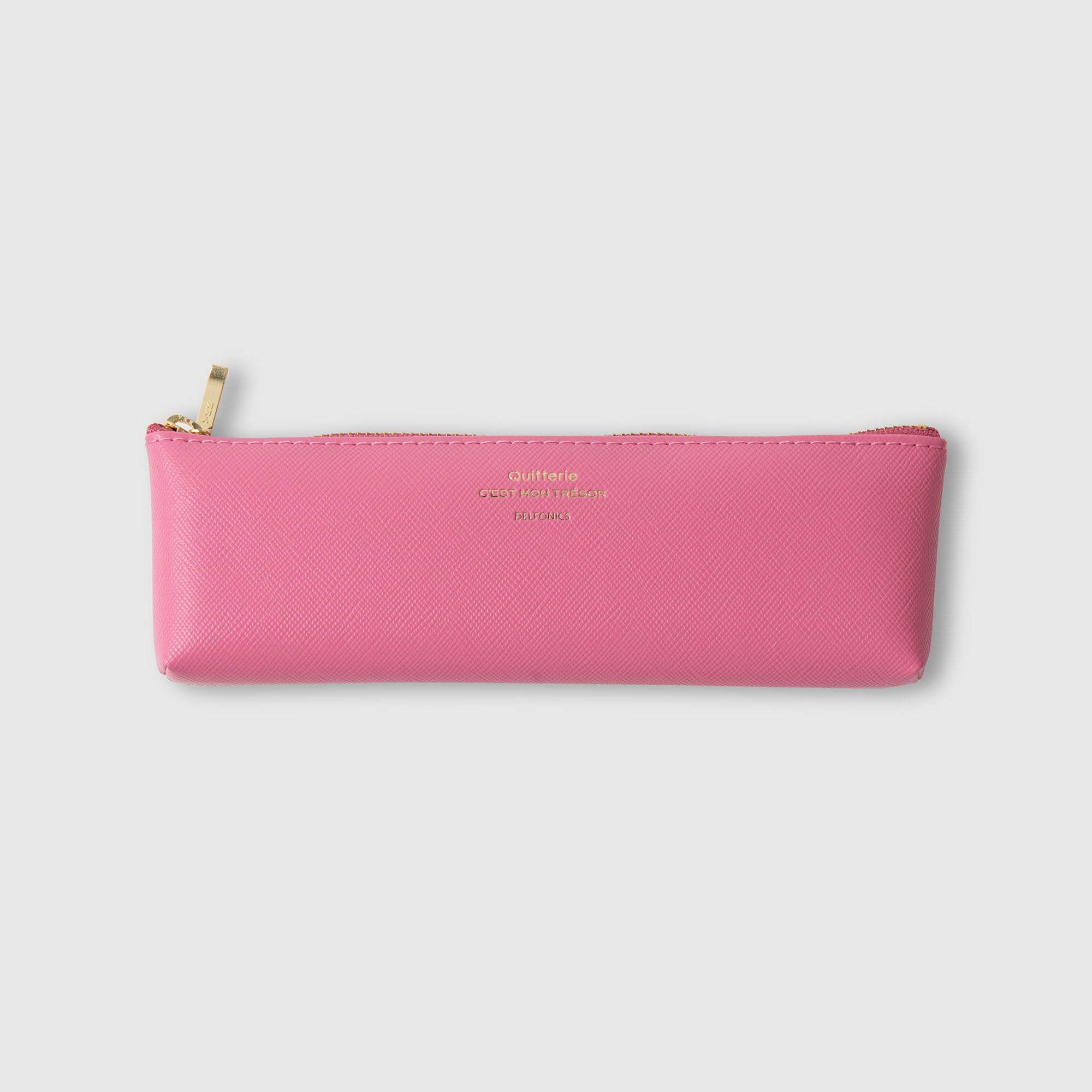 Ein rosa, rechteckiges „Quitterie“-Federmäppchen von Delfonics mit goldenem Reißverschluss und dezenter goldener Beschriftung auf der Vorderseite, gefertigt aus dem charakteristischen „Scotch-Grain-Optik“-Material von Delfonics, wird vor einem schlichten hellgrauen Hintergrund präsentiert.