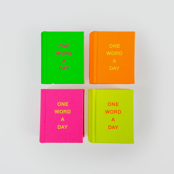 Vier OWAD Neon-Bücher von paperlux.store, in kräftigen Neonfarben – Grün, Orange, Pink und Gelb – gehalten und mit dem Titel „One Word a Day“ betitelt, sind stilvoll wie ein Mini-Notizbuch auf hellem Hintergrund angeordnet.