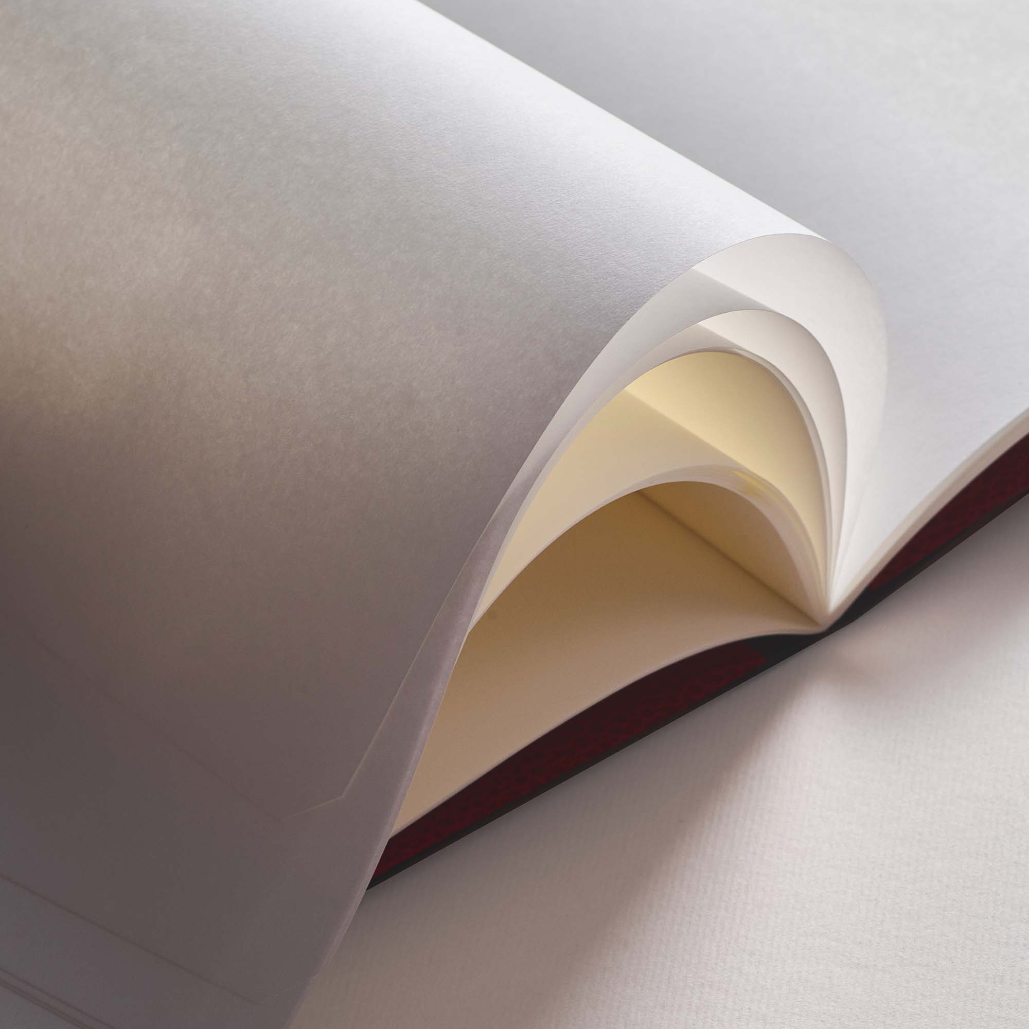 Eine Nahaufnahme von weißen und cremefarbenen Papierbögen, teilweise angehoben auf einer flachen Oberfläche mit sanfter Beleuchtung - ideal zum Basteln mit B96 Moss Green von paperlux.store oder zum Kombinieren mit Ihren Lieblingsprojekten.