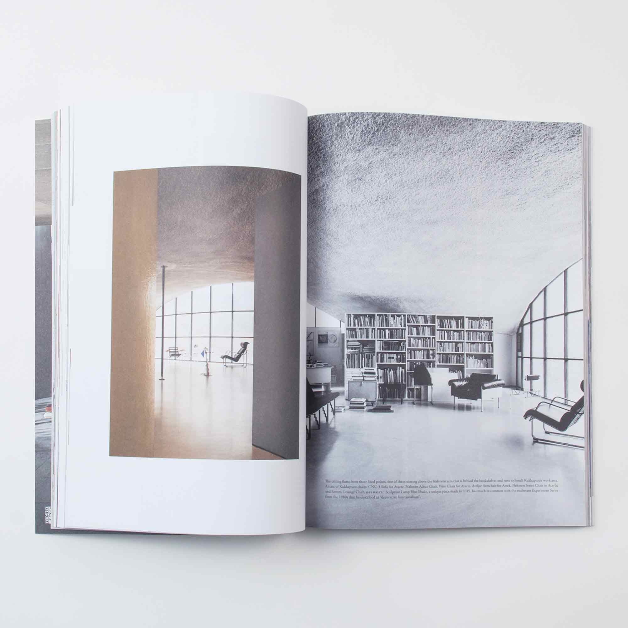 Das aufgeschlagene Ark Journal Vol. 9 offenbart zwei Seiten: Die linke Seite zeigt einen minimalistischen Raum mit geschwungenen Wänden und Loungesesseln, der Architektur Design in den Vordergrund stellt; die rechte Seite zeigt einen großzügigen Wohnbereich mit Regalen, Sofas und großen Fenstern, der kritische Debatten über moderne Inneneinrichtungen anregt.