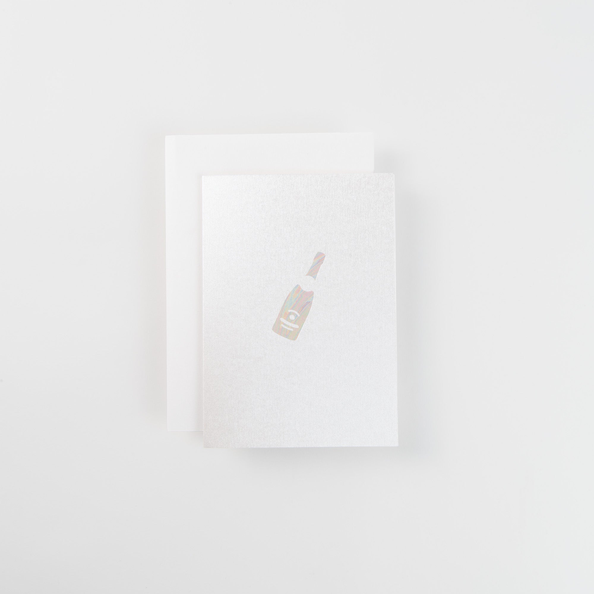 Die A6 Karte "Champagner" von paperlux.store ist eine weiße Grußkarte mit der Abbildung einer Champagnerflasche auf einem weißen Umschlag vor weißem Hintergrund.