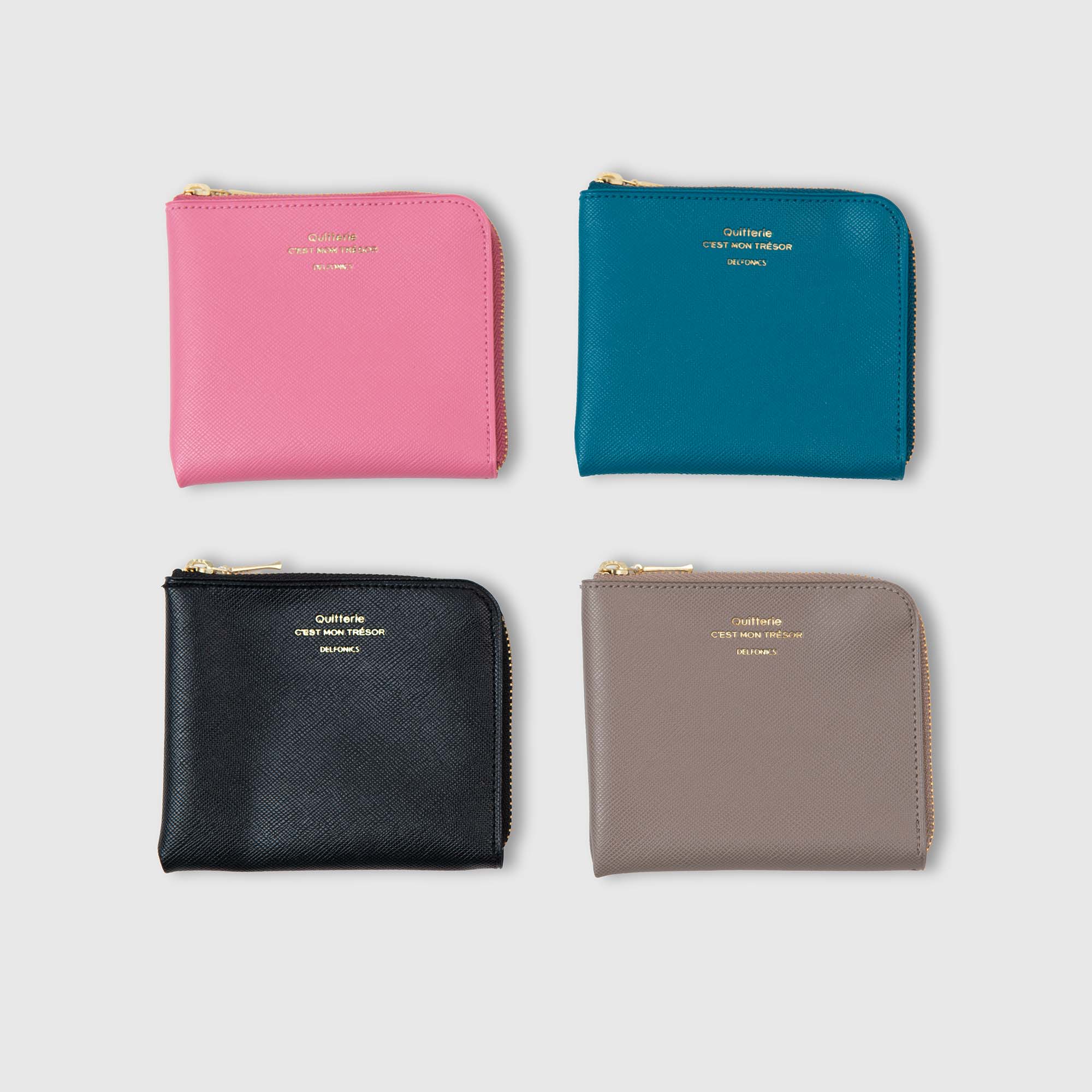 Vier Delfonics Quitterie Half Zip Card Case Kartenetuis in den Farben Rosa, Blaugrün, Schwarz und Taupe – jeweils mit einer stilvollen Oberfläche im Scotch-Grain-Look und eleganten goldenen Reißverschlüssen mit passender goldener Beschriftung auf der Vorderseite – sind in einem 2x2-Raster auf einem schlichten weißen Hintergrund angeordnet. Diese wasserabweisenden Kartenetuis von Delfonics verbinden Raffinesse mit alltäglicher Praktikabilität für Ihre Accessoire-Kollektion.