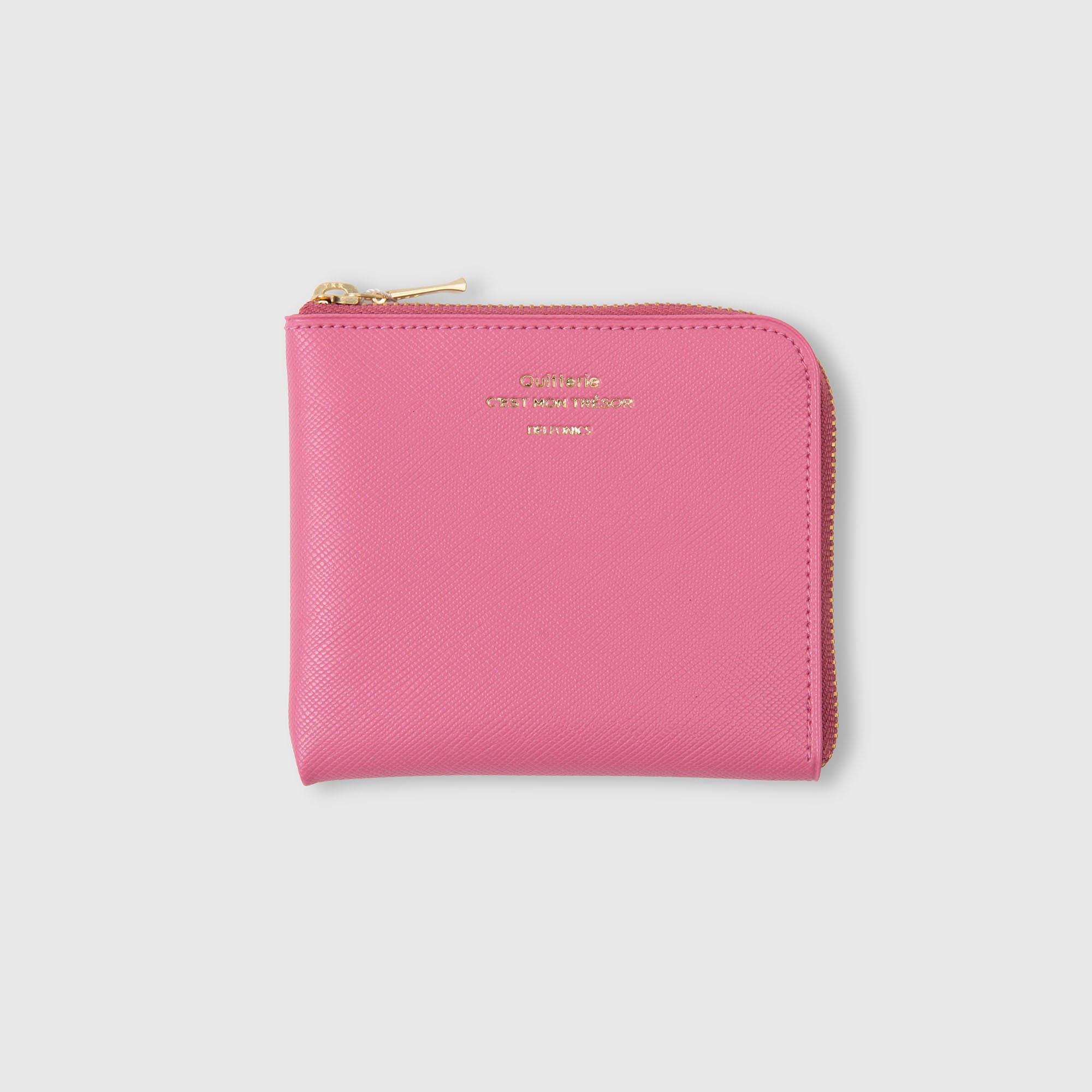 Ein rosa, quadratisches Delfonics Quitterie Kartenetui aus Leder im eleganten Scotch-Grain-Look mit goldenem Reißverschluss und dezenter goldener Beschriftung auf der Vorderseite wird vor einem schlichten hellgrauen Hintergrund präsentiert. Dieses Delfonics-Kartenetui ist sowohl stilvoll als auch wasserabweisend und verbindet Mode perfekt mit Funktionalität.