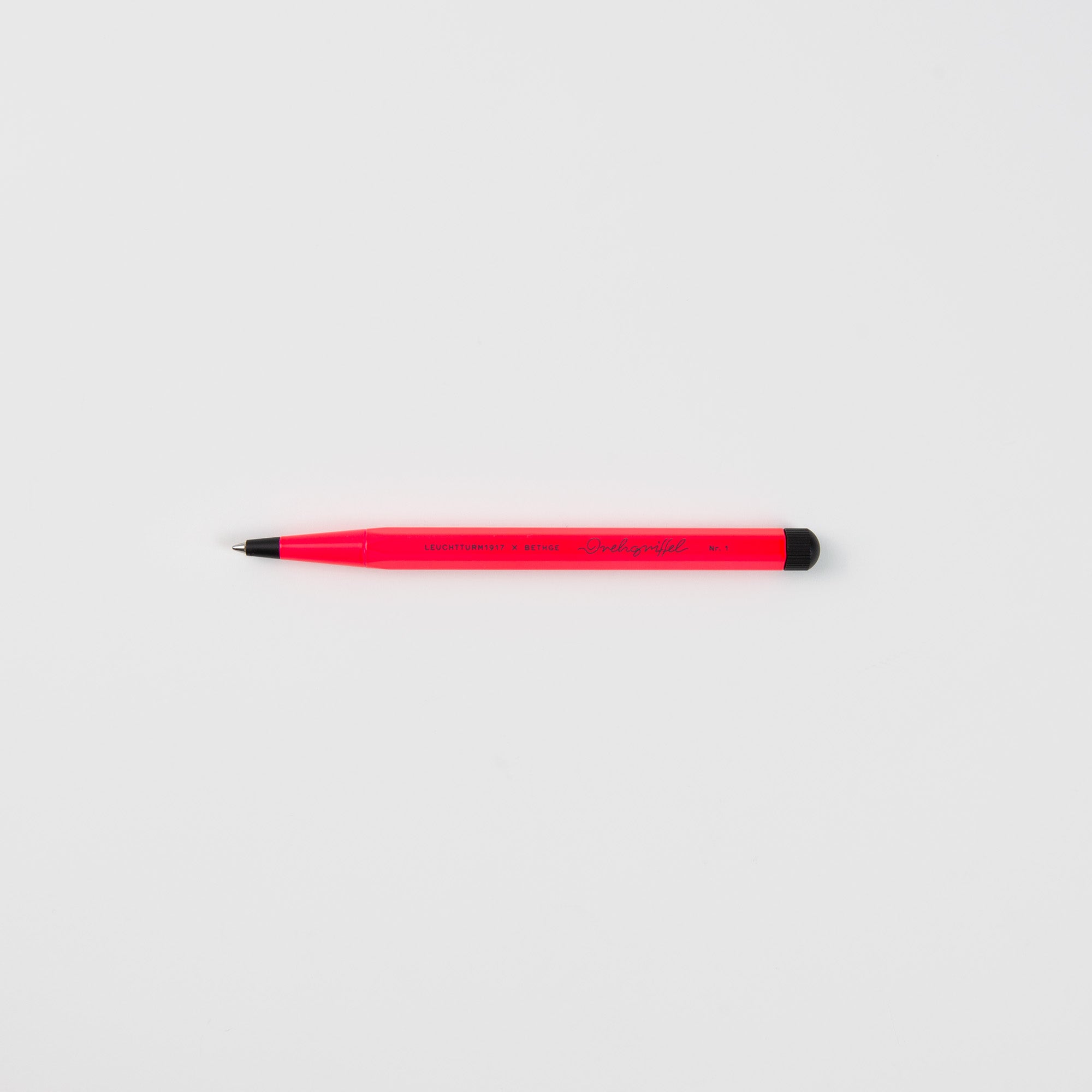 Ein roter Leuchtturm 1917 Drehgriffel No. 1 Luminous Edition mit schwarzer Spitze und Endkappe liegt waagerecht auf einem schlichten weißen Hintergrund.