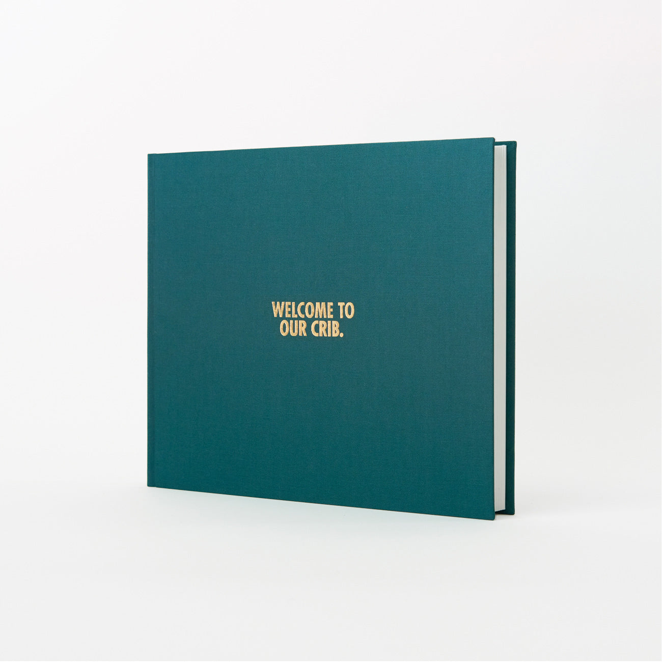 Vor weißem Hintergrund steht ein grünes Hardcover-Gästebuch „Welcome to our crib“ mit Goldprägung von „Wir sind Buchbinder“. Leicht geöffnet offenbart es seine Dicke – ein perfektes Geschenk aus Hamburg.