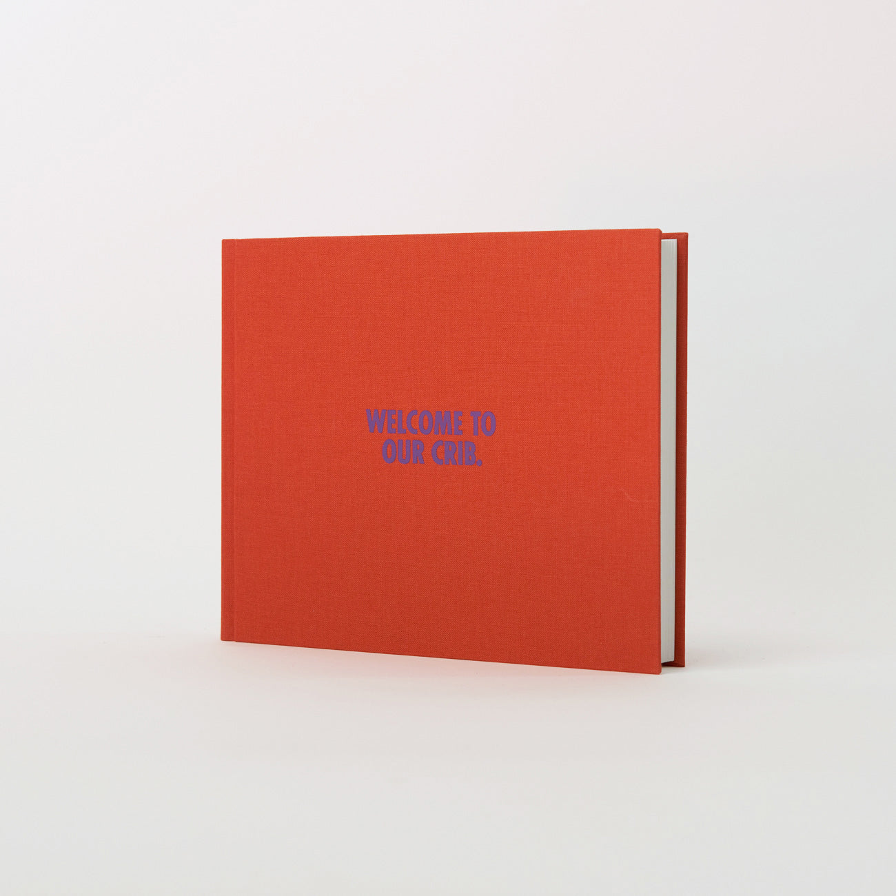 Ein Gästebuch mit festem Einband und dem Titel „Willkommen in unserer Krippe“ von We are Bookbinders, mit orangefarbenem Einband, stolz hergestellt in Hamburg, steht aufrecht vor einem schlichten weißen Hintergrund.
