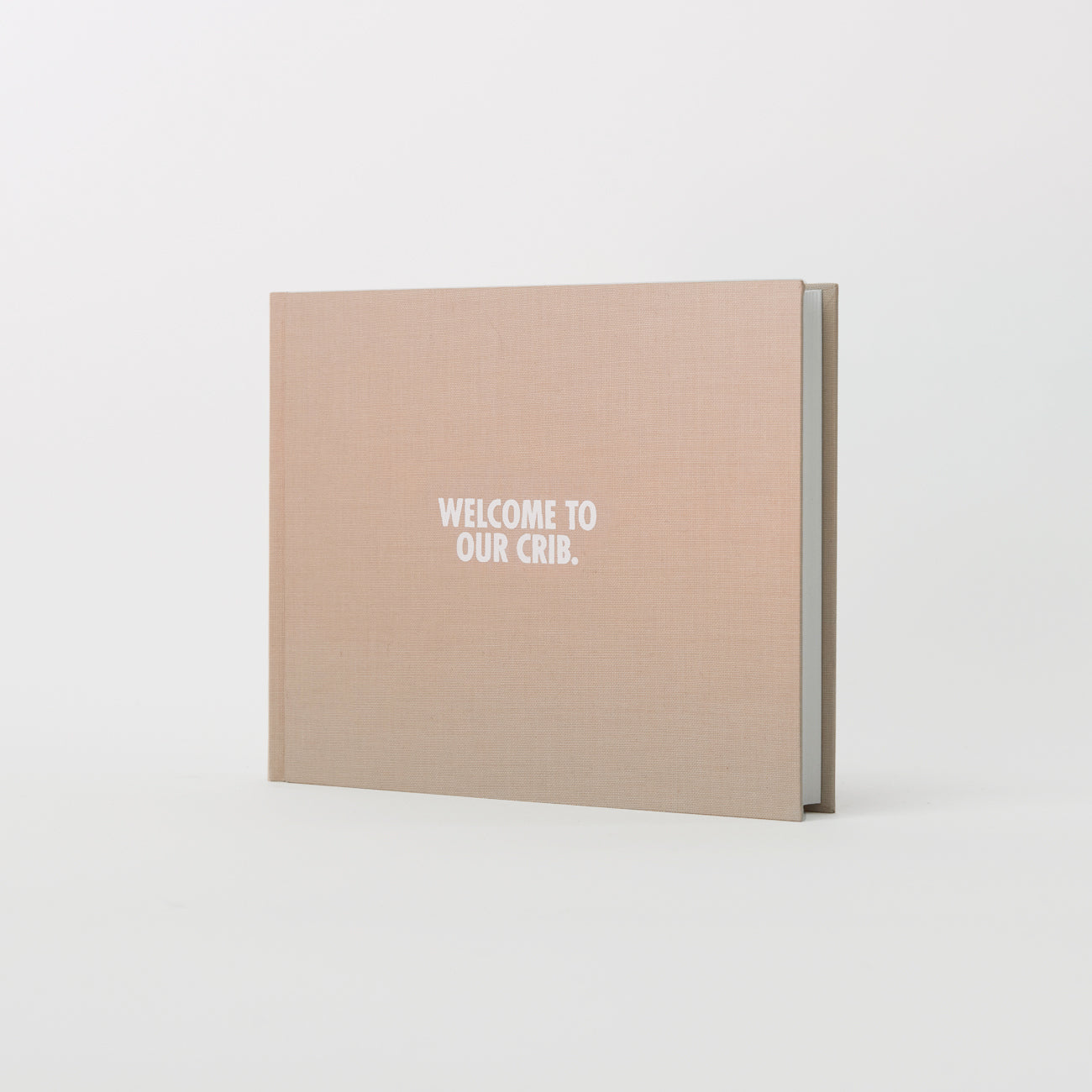 Das Gästebuch - Willkommen in unserer Krippe von We are Bookbinders ist ein geschlossenes beiges Fotoalbum mit dem Titel "WILLKOMMEN IN UNSERER KRIPPE." auf dem Cover, elegant auf weißem Hintergrund. Dieses charmante Erinnerungsstück aus Hamburg ist ein aufmerksames Geschenk.