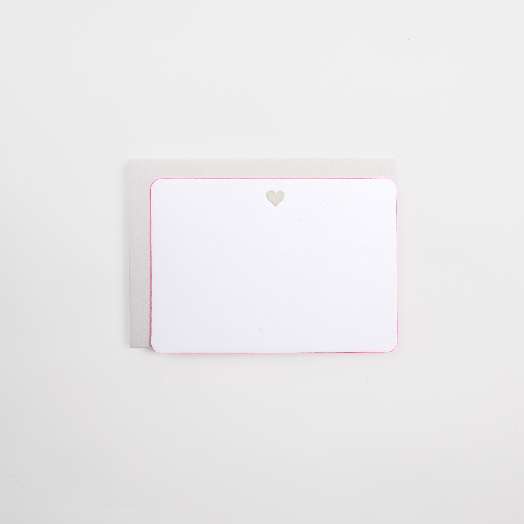 Die Grußkarte Icon mit Kuvert von Gmund ist eine leere weiße Letterpress-Karte auf Naturpapier mit abgerundeten Ecken und einem kleinen goldenen Herz in der oberen Mitte, gepaart mit einem hellgrauen Umschlag vor einem schlichten weißen Hintergrund.