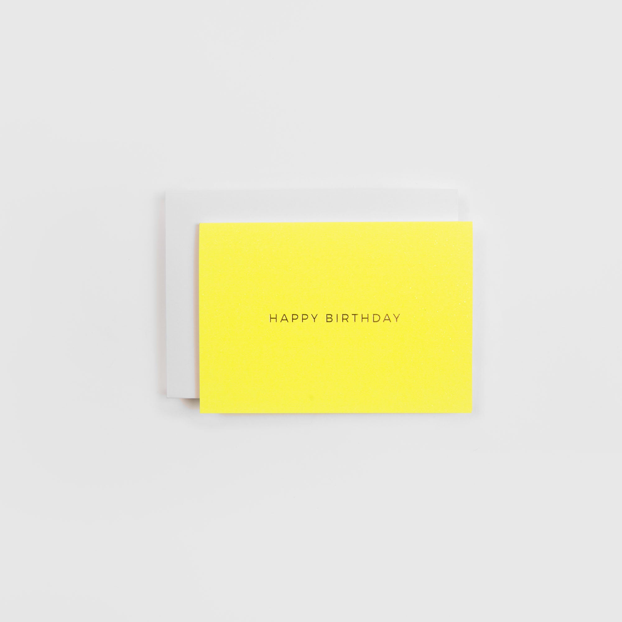 Das Gmund Kärtchen HAPPY BIRTHDAY ist eine leuchtend gelbe Letterpress-Karte mit dem Text HAPPY BIRTHDAY" in Großbuchstaben, der auf einem schlichten weißen Umschlag auf hellgrauem Hintergrund abgebildet ist.