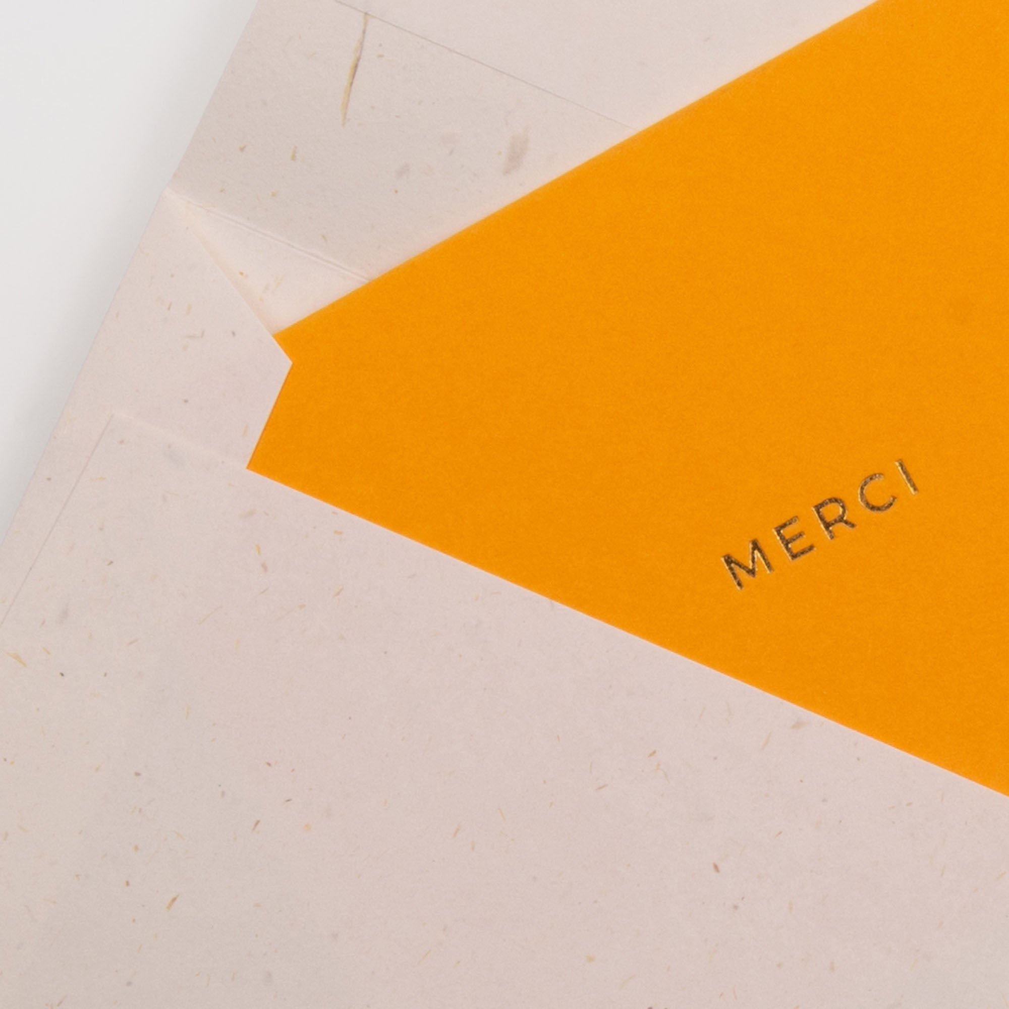 In einem weißen Umschlag steckt ein leuchtend orangefarbenes Kärtchen MERCI von Gmund aus Naturpapier mit schwarzem "MERCI"-Druck - perfekt als Dankeschön oder kleine bunte Notiz, um Ihre Dankbarkeit stilvoll auszudrücken.