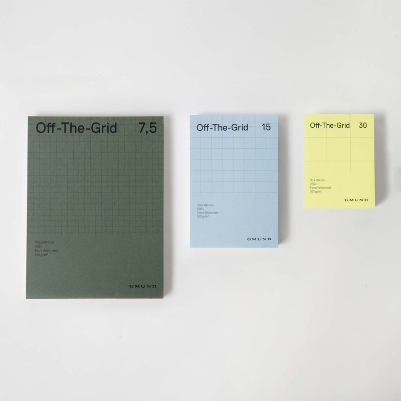 Auf weißem Hintergrund sind drei Notizblöcke „Off The Grid“ von Gmund aus Gmund-Papier abgebildet. Die großen dunkelgrünen, mittelblauen und kleinen gelben Notizbücher verfügen über ein innovatives Karo-Raster-Design mit „Off-The-Grid“-Etiketten mit den Aufschriften 7,5, 15 und 30.