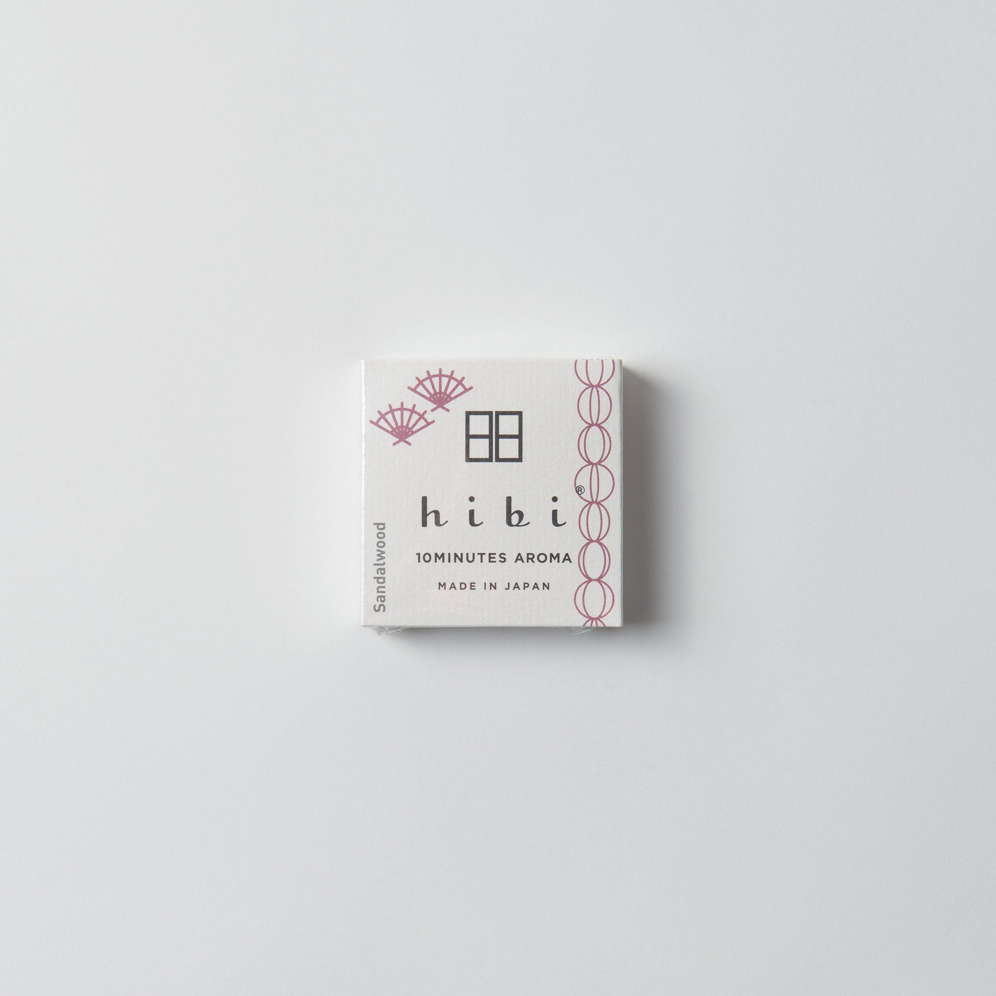 Die kleine, helle Hibi-Duftstreichhölzer-Box ist mit dekorativen violetten Akzenten versehen und enthält die Aufschrift „10 MINUTES AROMA“, „Sandalwood“ und „Made in Japan“, die einen natürlichen Duft einfangen. Sie ähnelt japanischen Streichhölzern und ruht elegant auf einem schlichten weißen Hintergrund.