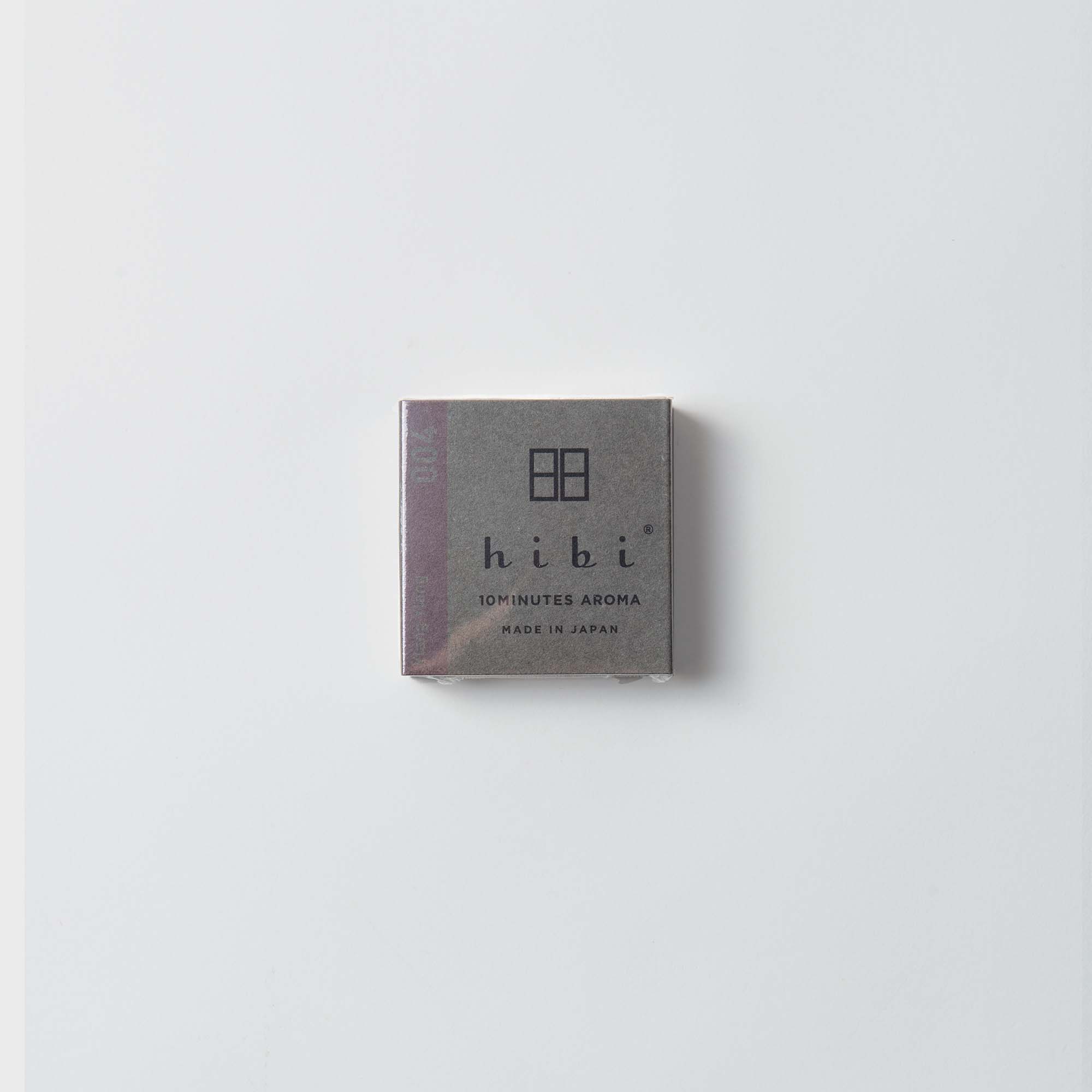Eine kleine, quadratische graue Schachtel mit minimalistischem Design und der Aufschrift „Hibi Duftstreichhölzer“ und „MADE IN JAPAN“ steht vor weißem Hintergrund. Darin befinden sich japanische Streichhölzer, die ein natürliches Aroma aus Dufthölzern freisetzen.