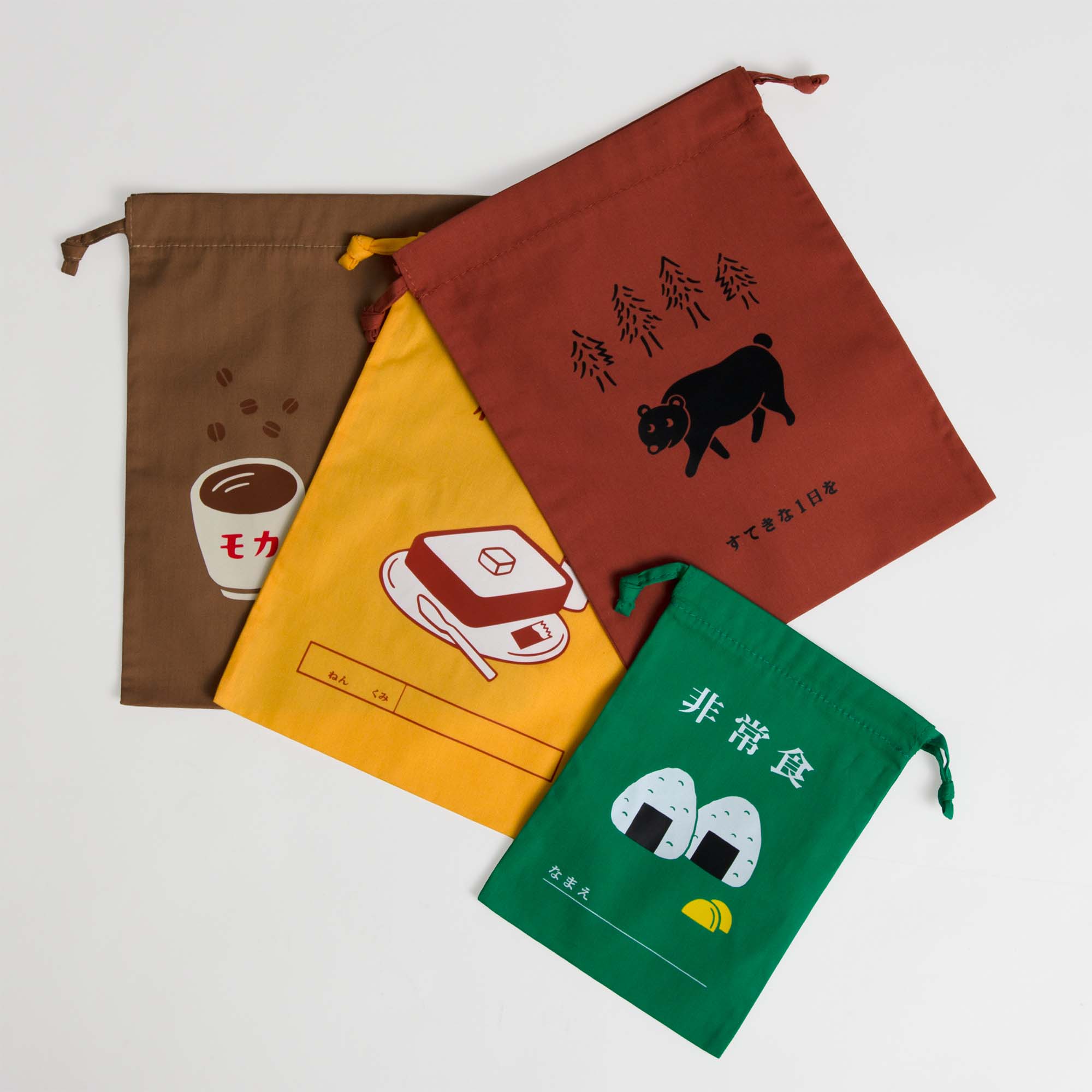 Vier farbenfrohe Hightide Beutel mit Kordelzug Medium mit japanischem Text und Lebensmittelillustrationen - eine Kaffeetasse, eine Brotdose, zwei Reisbällchen und eine Kuh - sind überlappend auf einem weißen Hintergrund angeordnet.