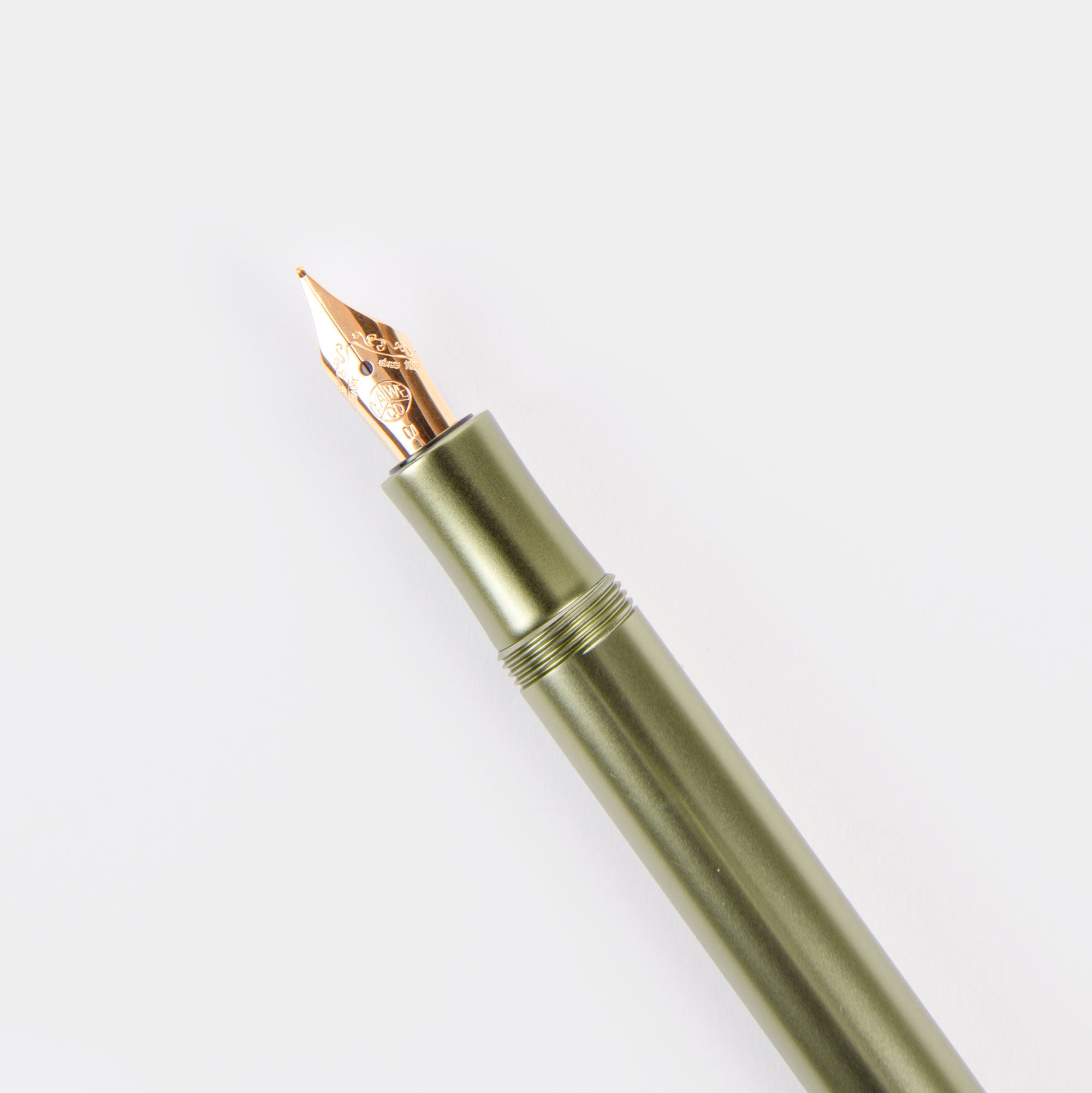 Ein grüner Kaweco Füllhalter - limitierte Edition Olivine mit einer Goldfeder wird vor einem weißen Hintergrund präsentiert und hebt sein elegantes Metalldesign und die verzierten Federdetails hervor, ohne die Kappe zu zeigen.