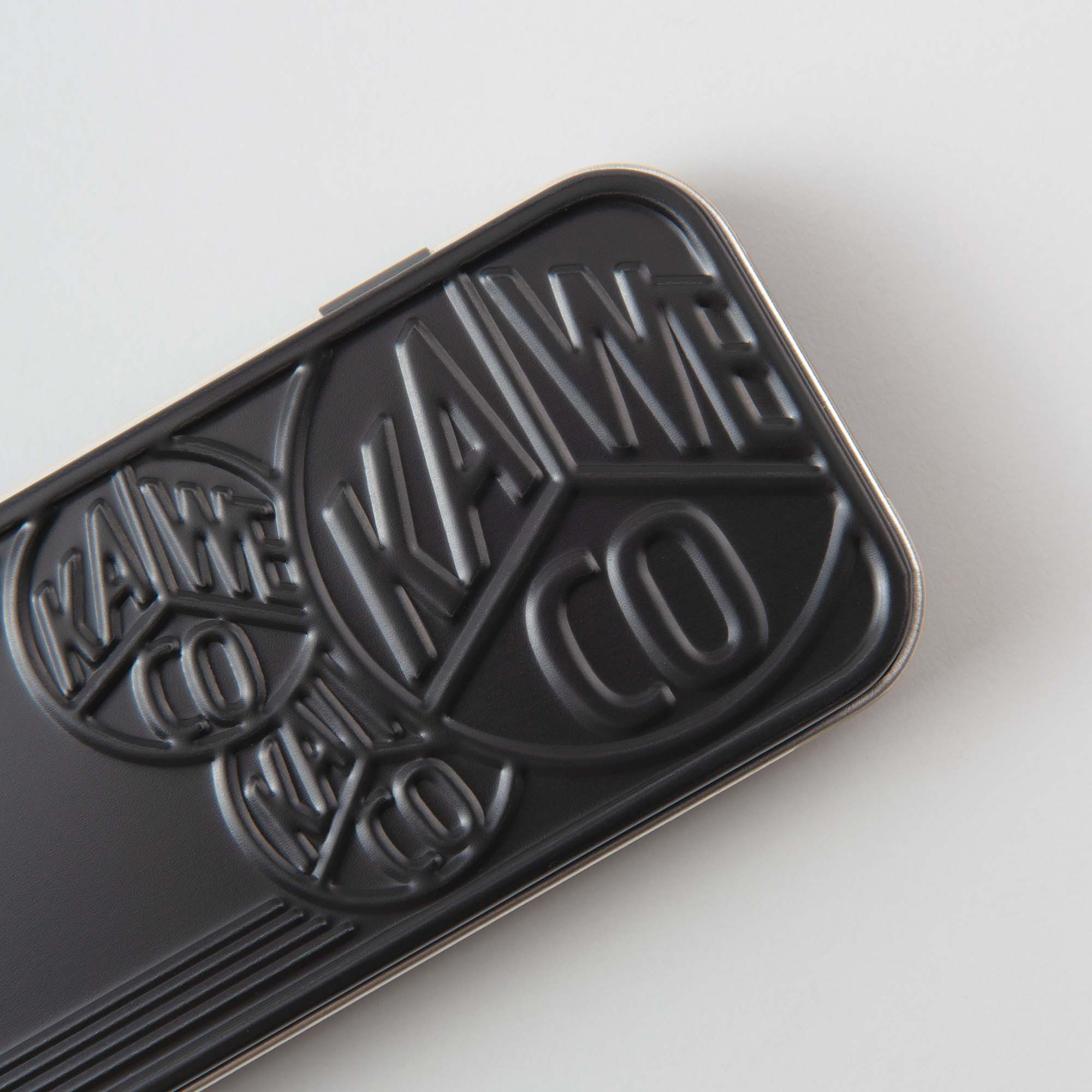 Eine Nahaufnahme zeigt ein elegantes schwarzes Prägedesign mit runden „Kaweco“-Logos, das Ihre Lern- und Lesestunden bereichert. Dieses Produkt verleiht vor einem strahlend weißen Hintergrund Stil und Eleganz.