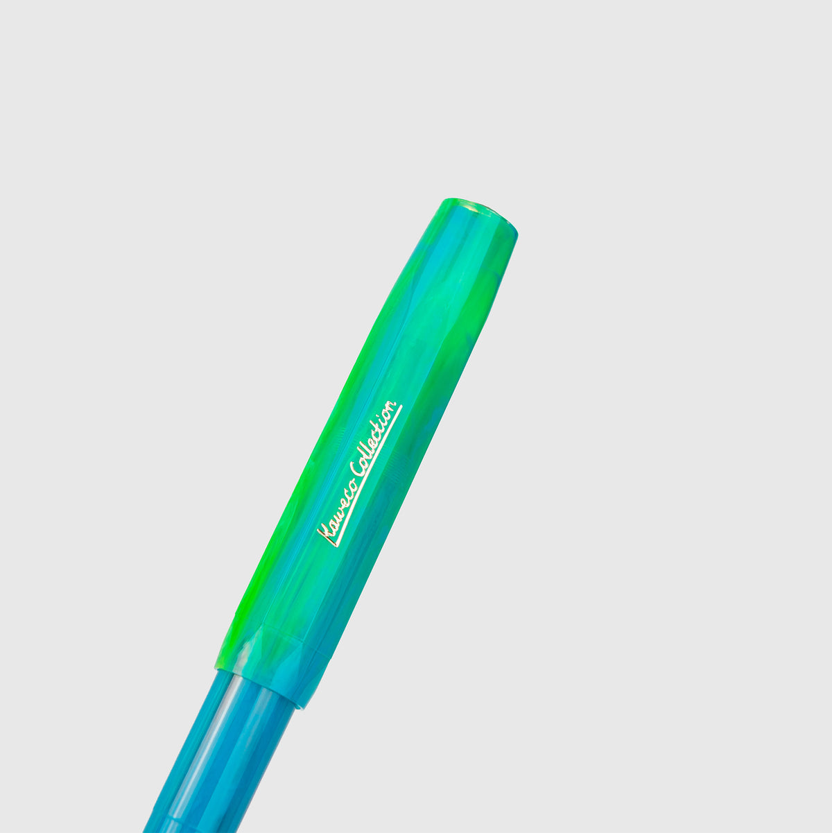 Eine Nahaufnahme des Füllers „Kaweco Collection – Marble Ocean“ von Kaweco mit einem marmorierten blau-grünen Design und einer Kappe mit dem Prägeaufdruck „Kaweco Collection“ vor einem schlichten hellgrauen Hintergrund.