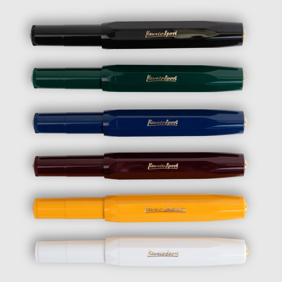 Sechs Kaweco Classic Sport – Füllhalter in Schwarz, Dunkelgrün, Marineblau, Burgunderrot, Gelb und Weiß, horizontal angeordnet und von oben betrachtet.