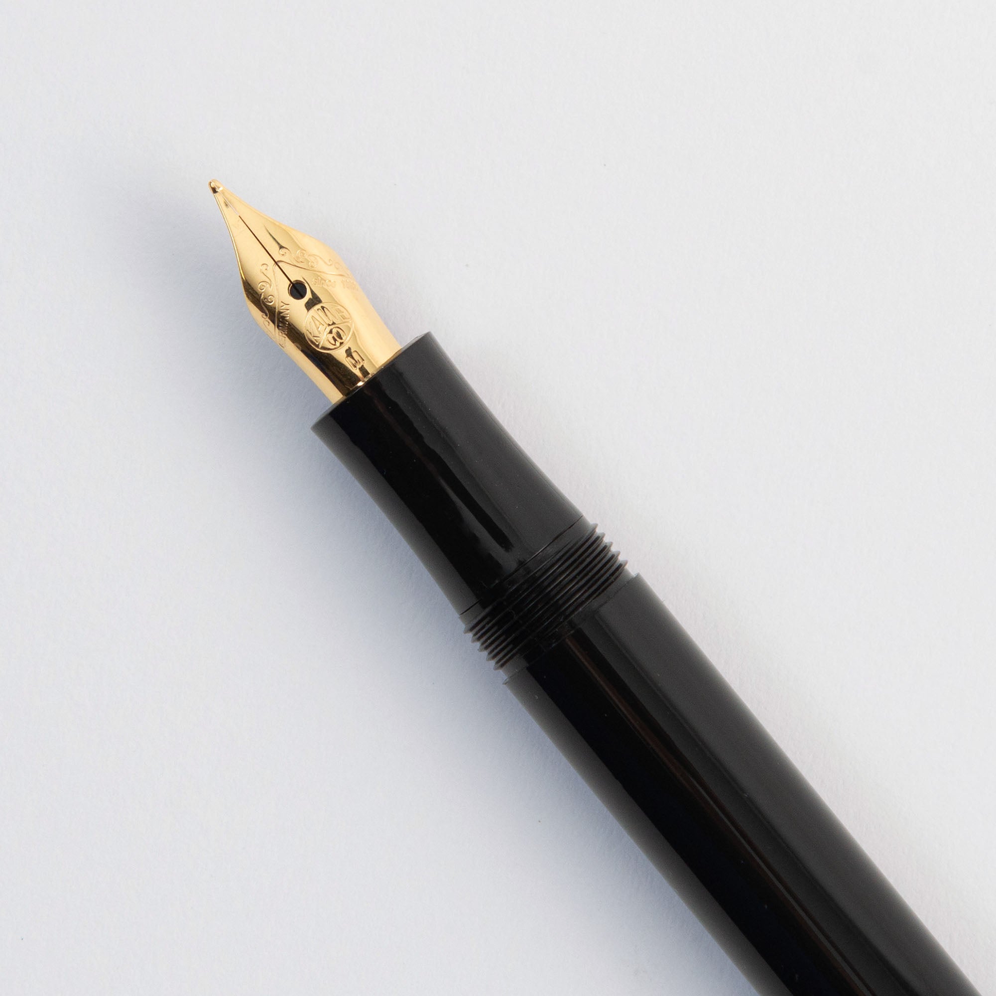 Eine Nahaufnahme der Feder eines Kaweco Classic Sport - Füllhalter von Kaweco, mit einer Goldfeder vor einem schlichten weißen Hintergrund.