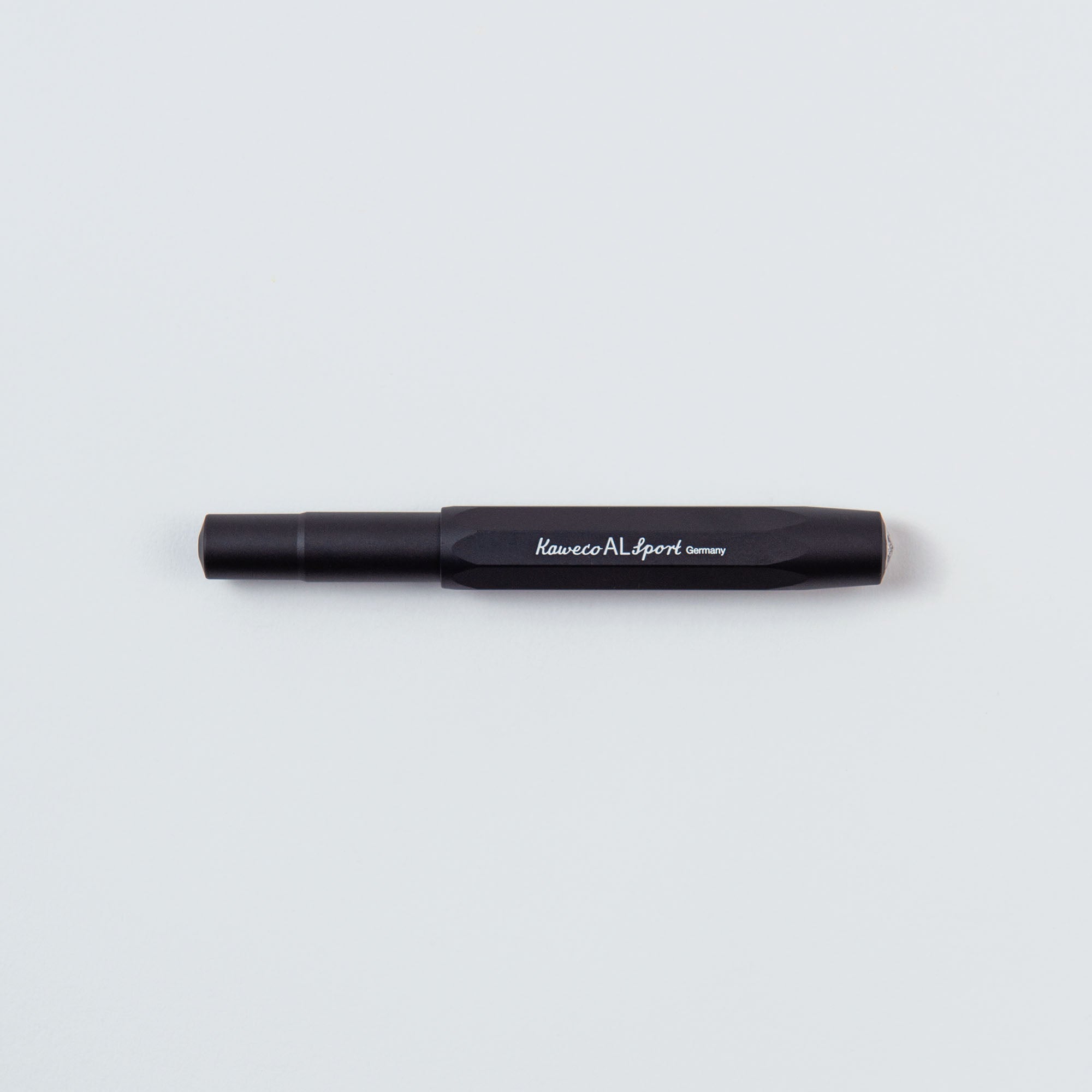 Der Kaweco Füllhalter M – Aluminium, ein kompakter schwarzer Füllhalter mit zylindrischem Design, ruht auf schlichtem weißem Untergrund. Er verfügt über einen eleganten Aluminiumschaft und trägt den Schriftzug „Kaweco AL Sport Germany“ – eine Kombination aus zeitloser Handwerkskunst und Kompaktgröße.