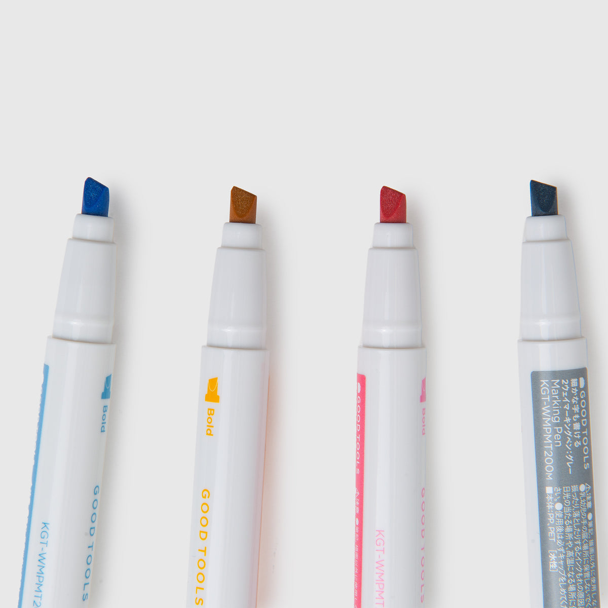 Vier weiße Kokuyo-Doppelseiten-Markierungsstifte mit blauen, goldenen, rosa und dunkelblauen Spitzen, horizontal nebeneinander angeordnet.