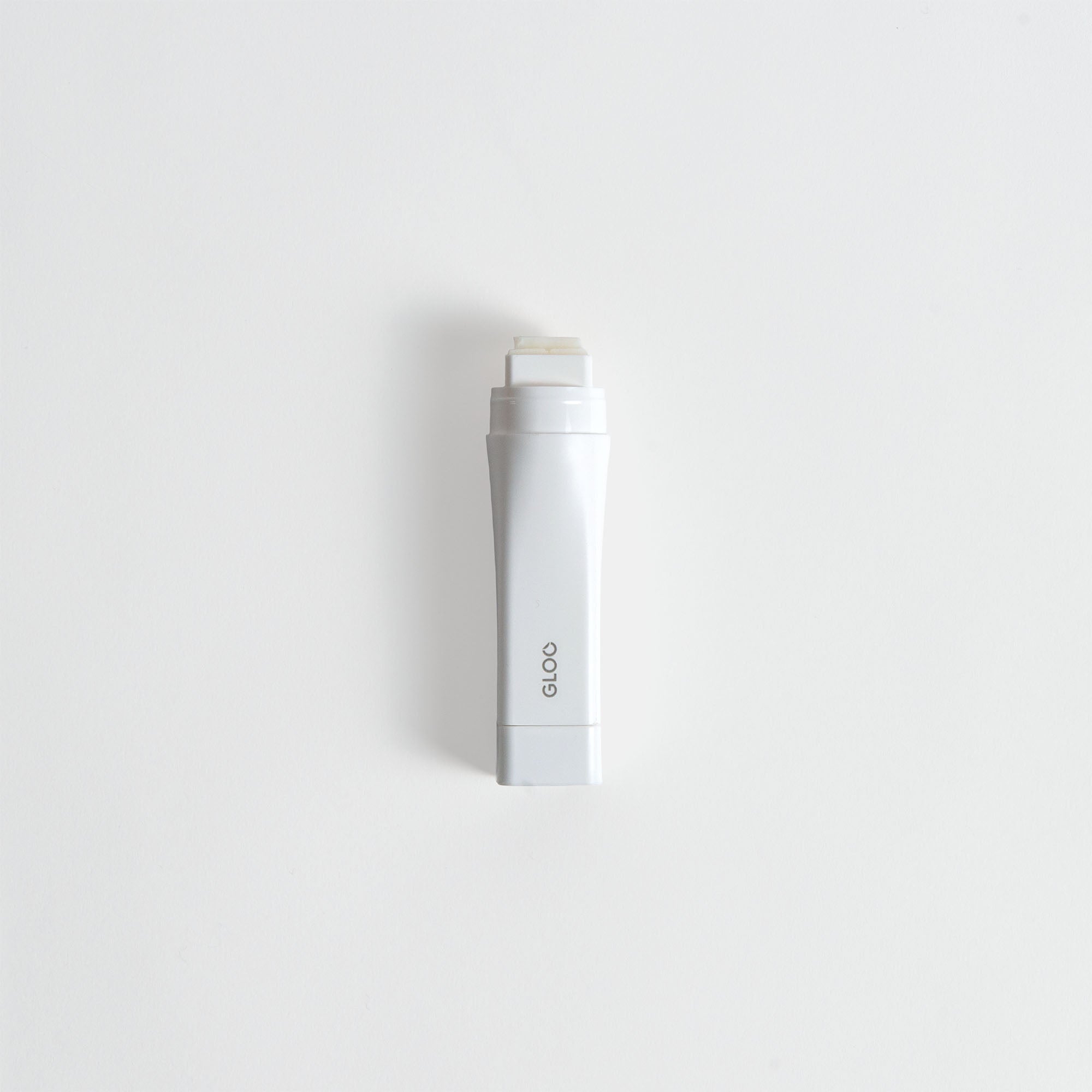 Ein weißer Kokuyo Gloo Klebestift - Permanent Klebestift von Kokuyo mit einem rechteckigen Design steht aufrecht auf einem schlichten weißen Hintergrund.