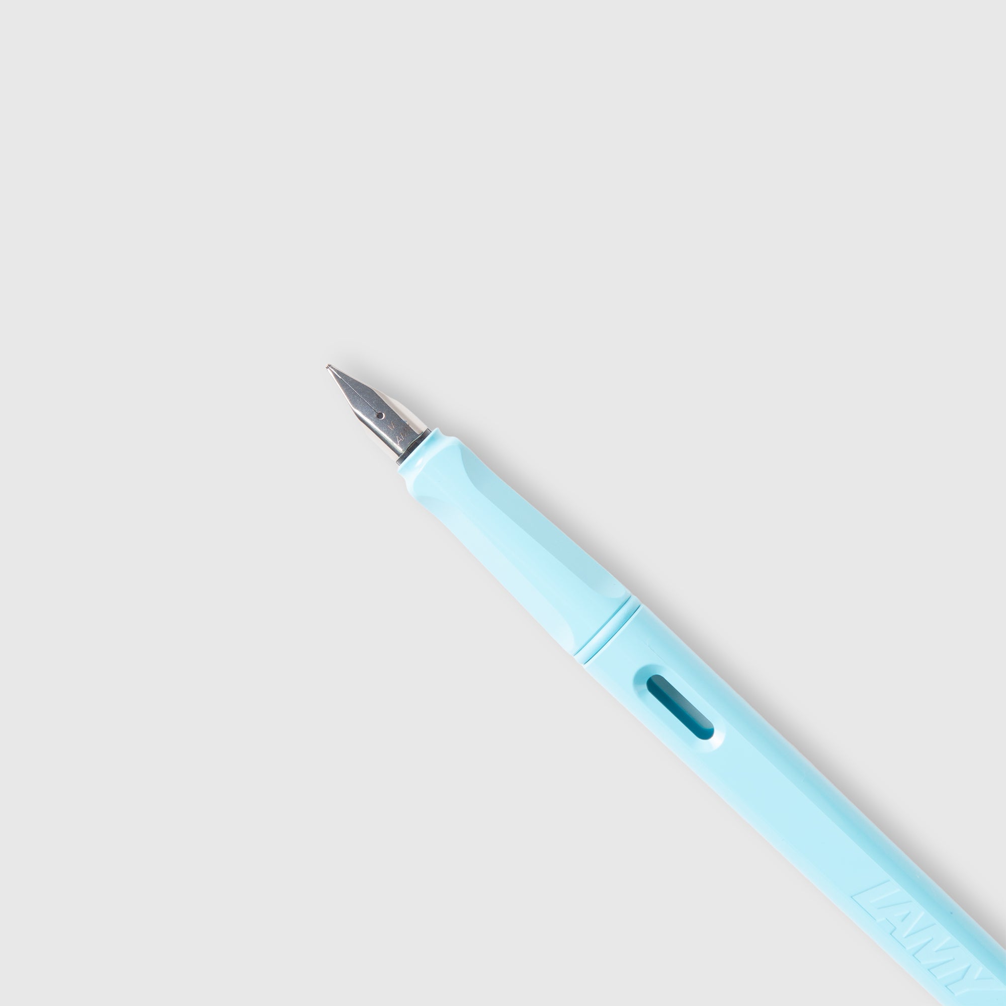 Ein hellblauer LAMY safari Füllhalter von Lamy, gefertigt aus ASA-Kunststoff mit einer Silberfeder, ist diagonal auf einem einfarbigen hellgrauen Hintergrund abgebildet.