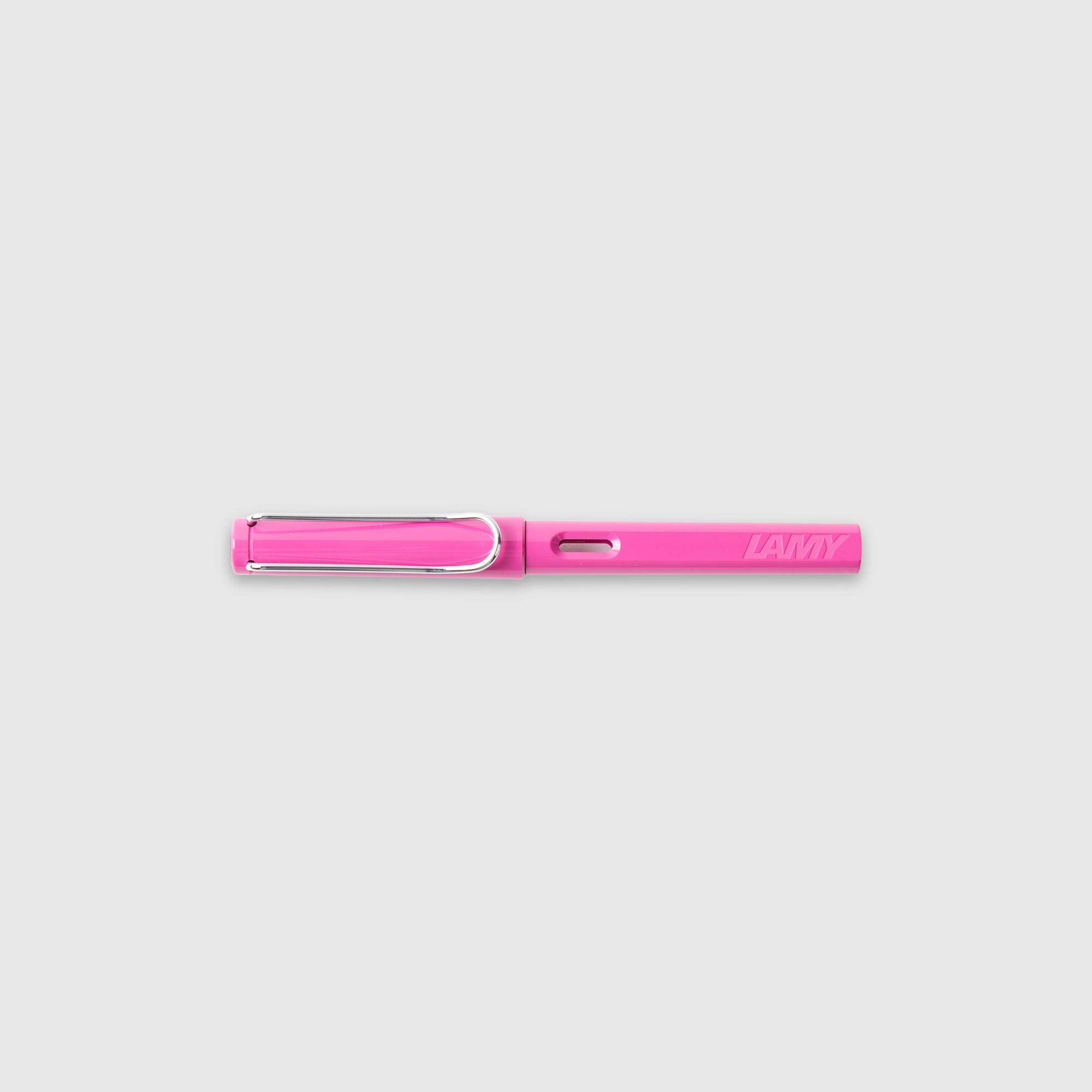 Ein rosa LAMY Safari Füllhalter von Lamy mit Edelstahlfeder und einem silbernen Clip liegt waagerecht auf einem schlichten hellgrauen Hintergrund.